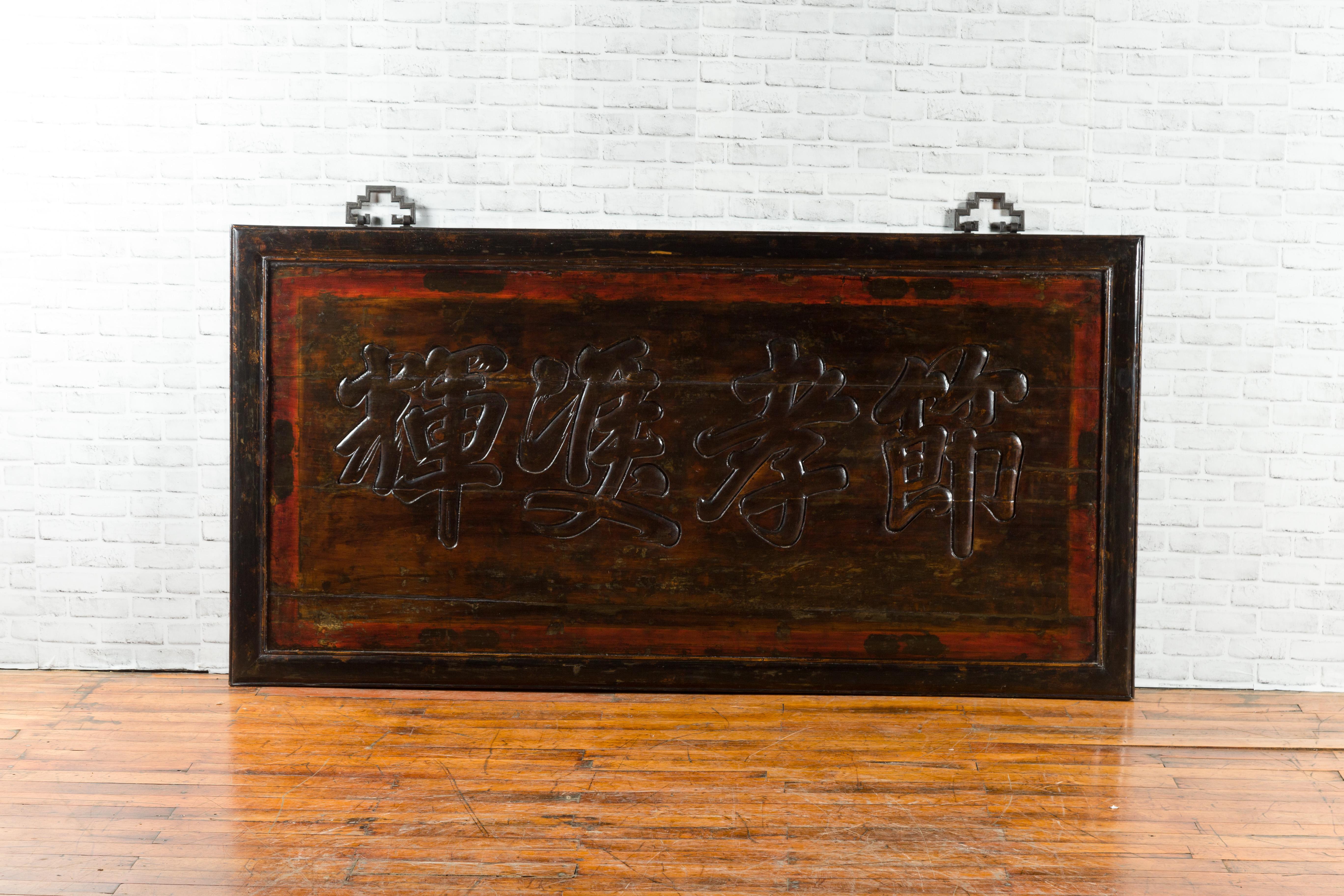 A large Chinese hand carved shop sign from the early 20th century, with calligraphy. Created in China during the early years of the 20th century, this shop sign features Chinese characters carved in low-relief. The panel is lacquered with a dark