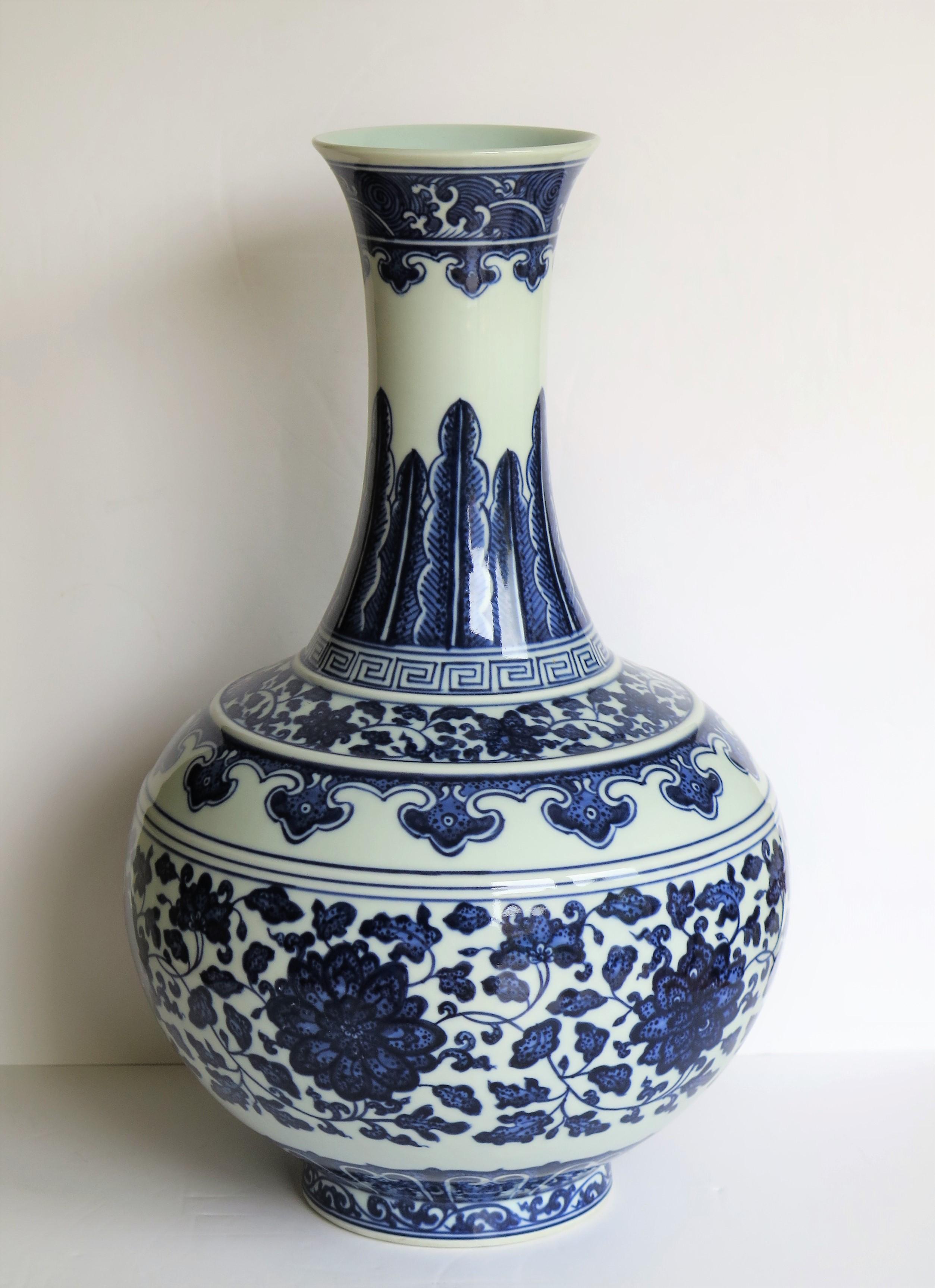 This is a large, elegant porcelain Chinese Export bottle vase, hand painted in a blue and white scrolling peony pattern with a six character seal mark and dating to the mid-20th century.

This bottle vase is very well potted on a low foot with a