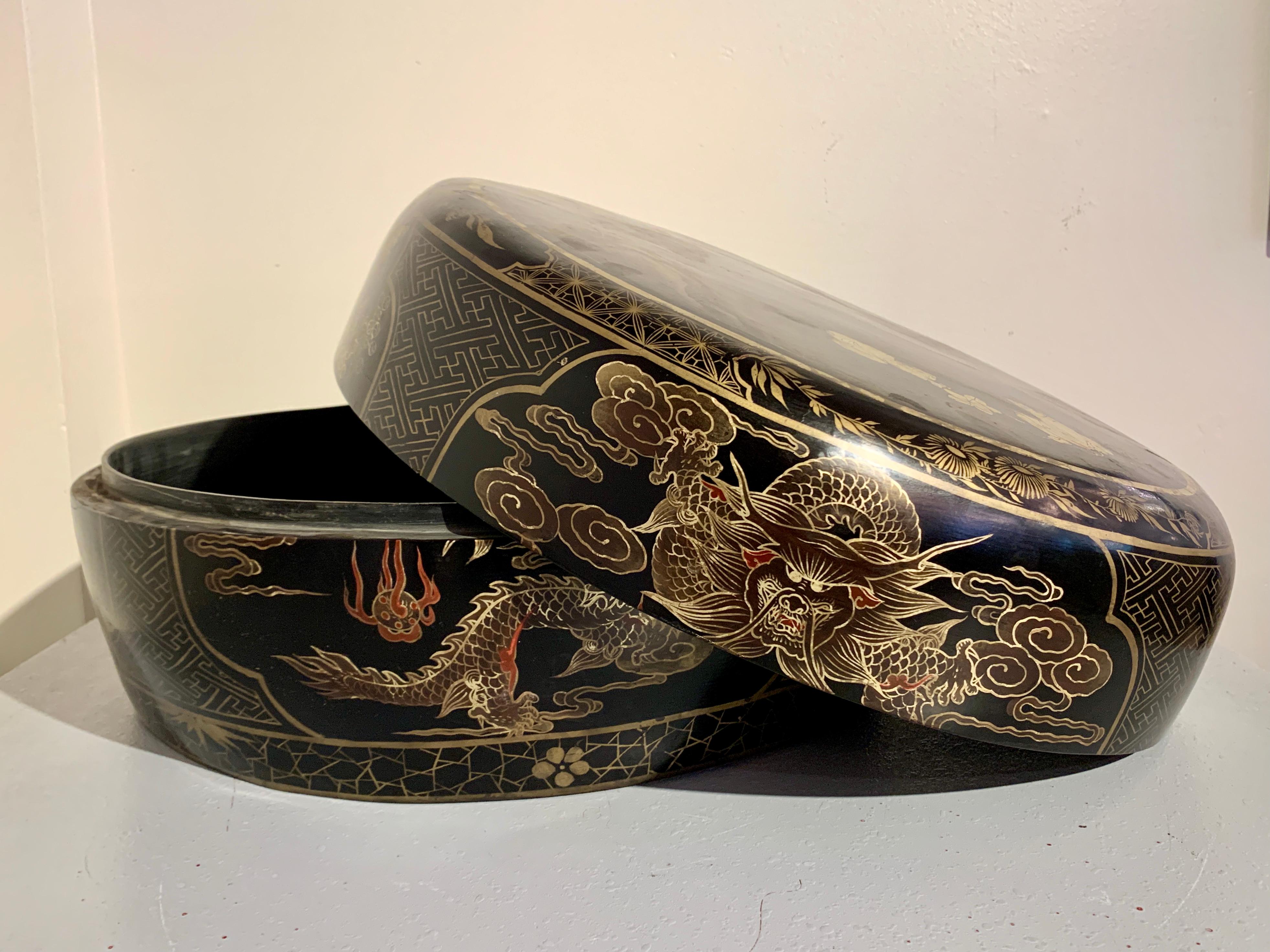 A very large Chinese round black lacquer and gilt painted box, made for the export market, mid 20th century, China.

The round black lacquer box of impressive proportions, and decorated with beautiful gilt painting. The top of the box features a