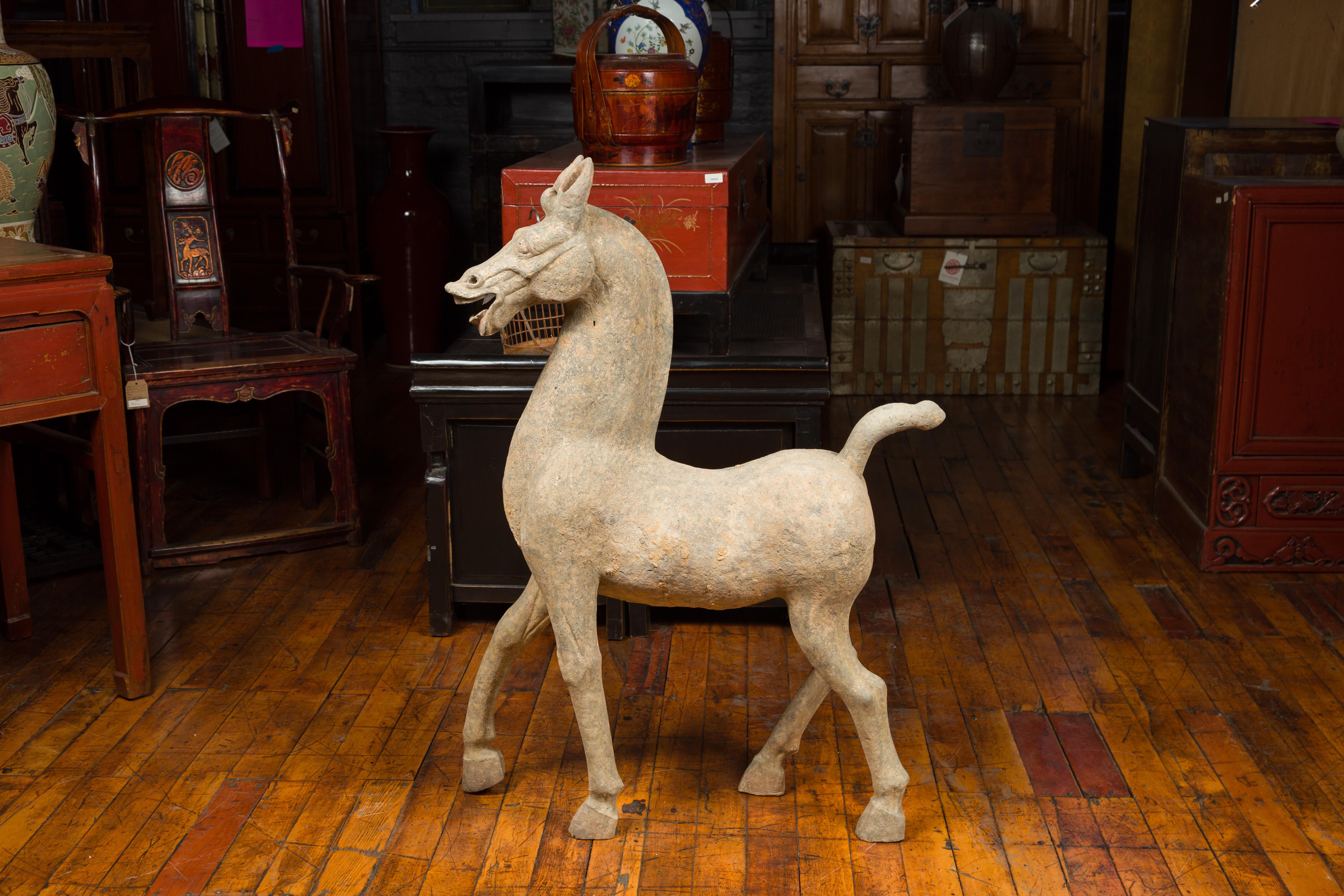 A large Chinese Han dynasty period terracotta walking horse with mineral deposits, circa 202 BC-200 AD. Handcrafted in China during the prestigious Han dynasty, this large and unusual Chinese terracotta horse is depicted walking in a very animated