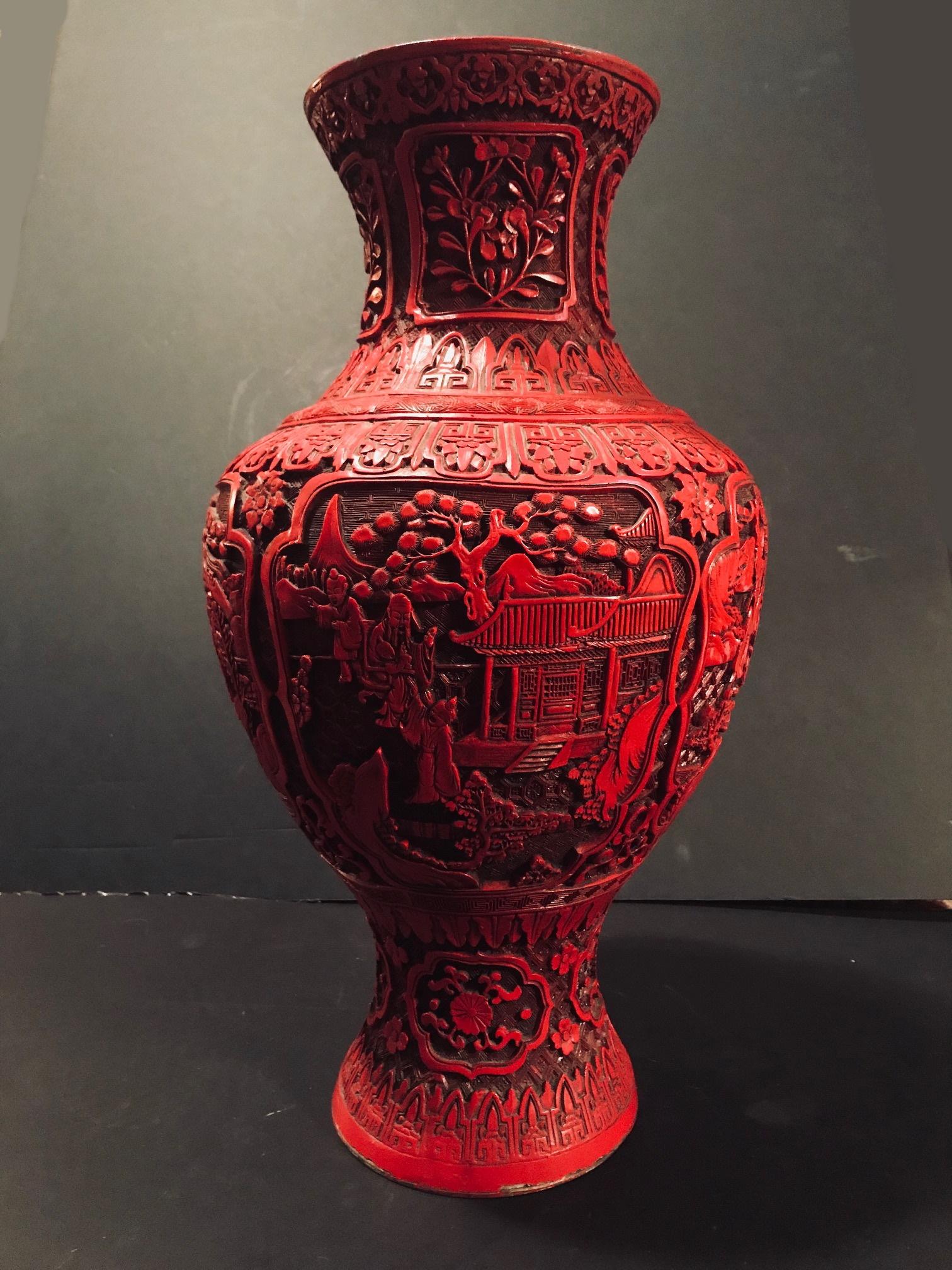 This is a large cinnabar vase of opulent proportions. It is carved in relief with floral decoration on a lattice-work background over a brass baluster form body. There are different motifs in the elaborately carved surface, including full figural