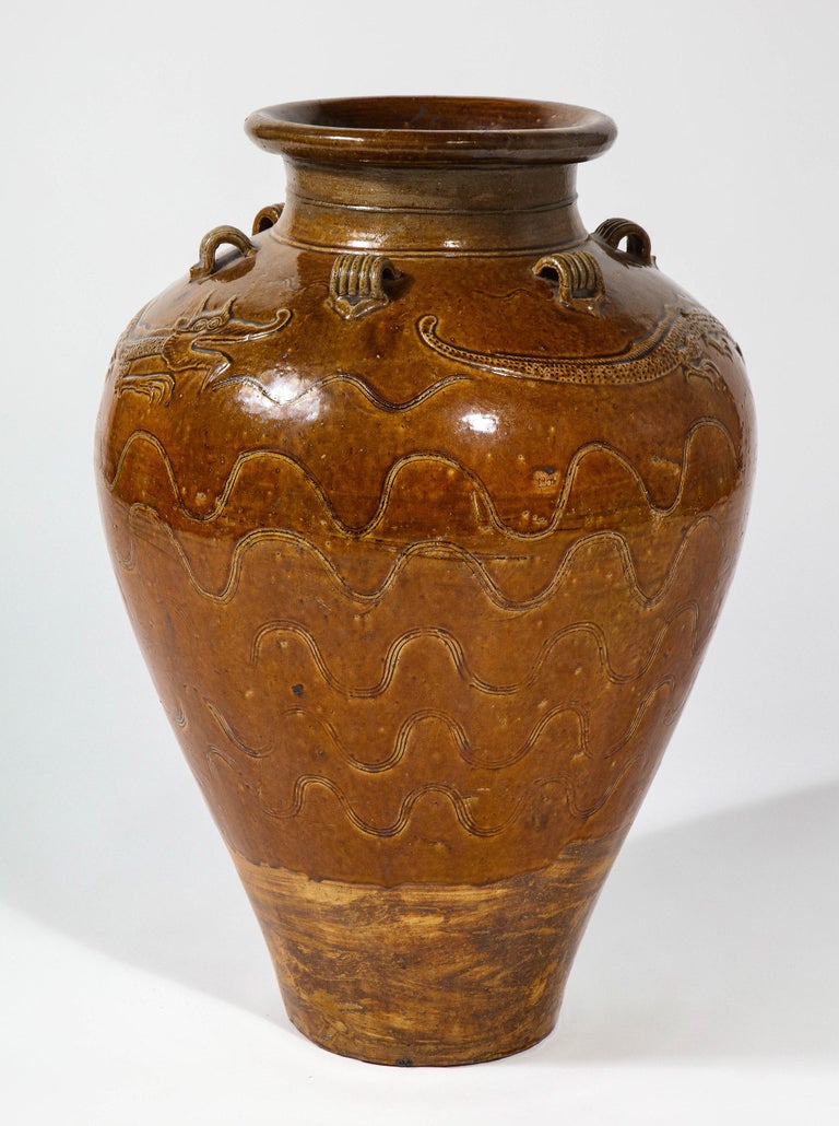 An ochre glazed stoneware storage jar, known as a Martaban jar, Ming dynasty, 15th-16th century.
Decorated with a pair of undulating dragons molded in low relief, with incised clouds or waves below and lug handles above.