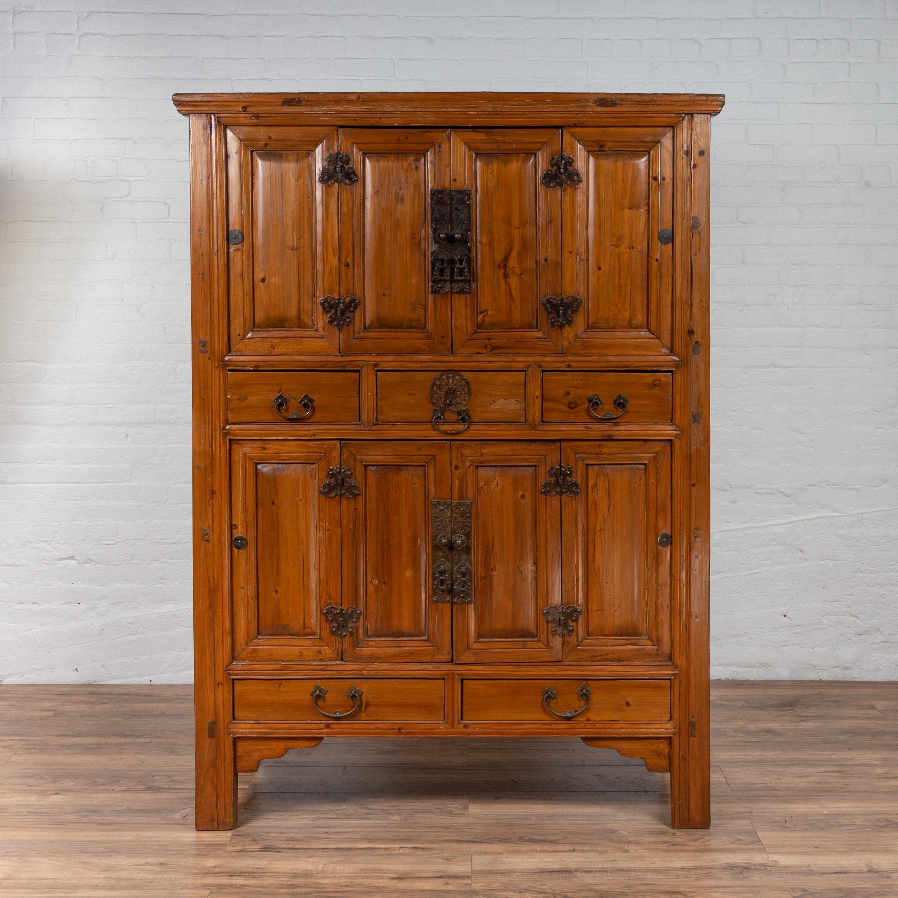 A Chinese Qing dynasty style wooden cabinet from the late 19th century, with paneled doors, drawers and butterfly iron hardware. Born in China during the late 19th century, this exquisite wooden cabinet features a molded cornice, sitting above an