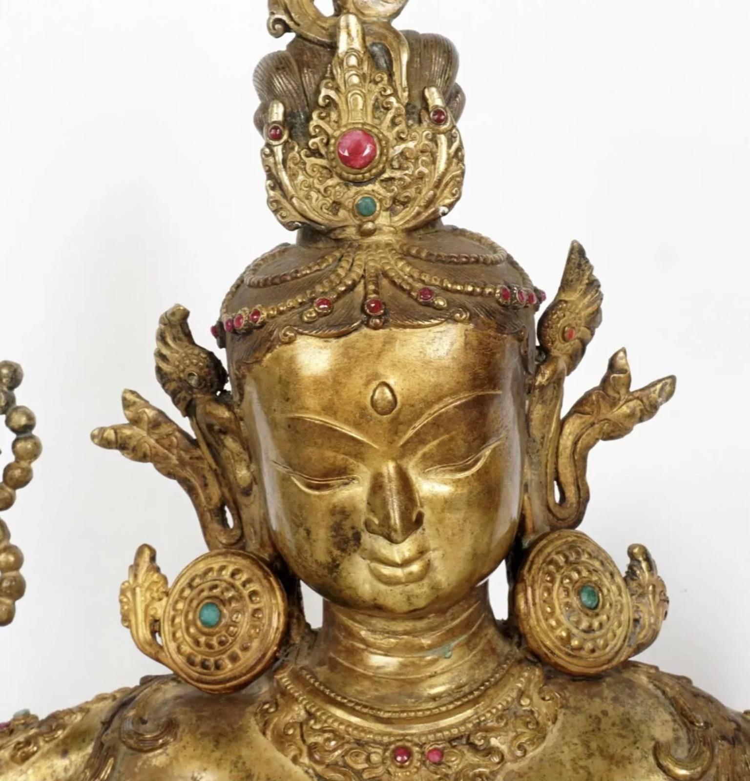 Chinese Tibetan gilt bronze Bodhisattva Buddha figure of Vasudhara (stream of gems), with a slim body, six arms with five holding precious objects, with the face slightly smiling. The body is slightly thin and dexterous. Cabochon inset semi precious
