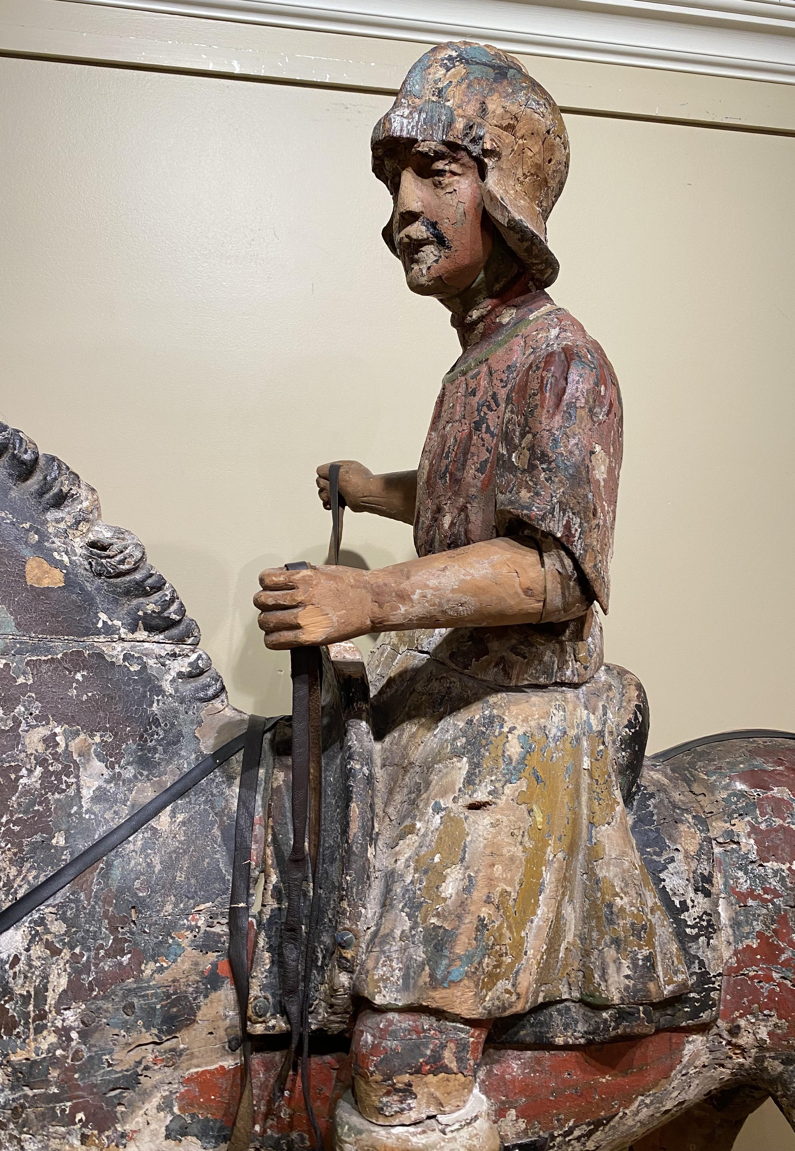 A wonderful Chinese polychrome carved wooden warrior sculpture on horseback on an oval wooden base, its body hollowed out on one side, with great surface and patina. Probably dates to the 18th century in good overall condition, with paint losses,