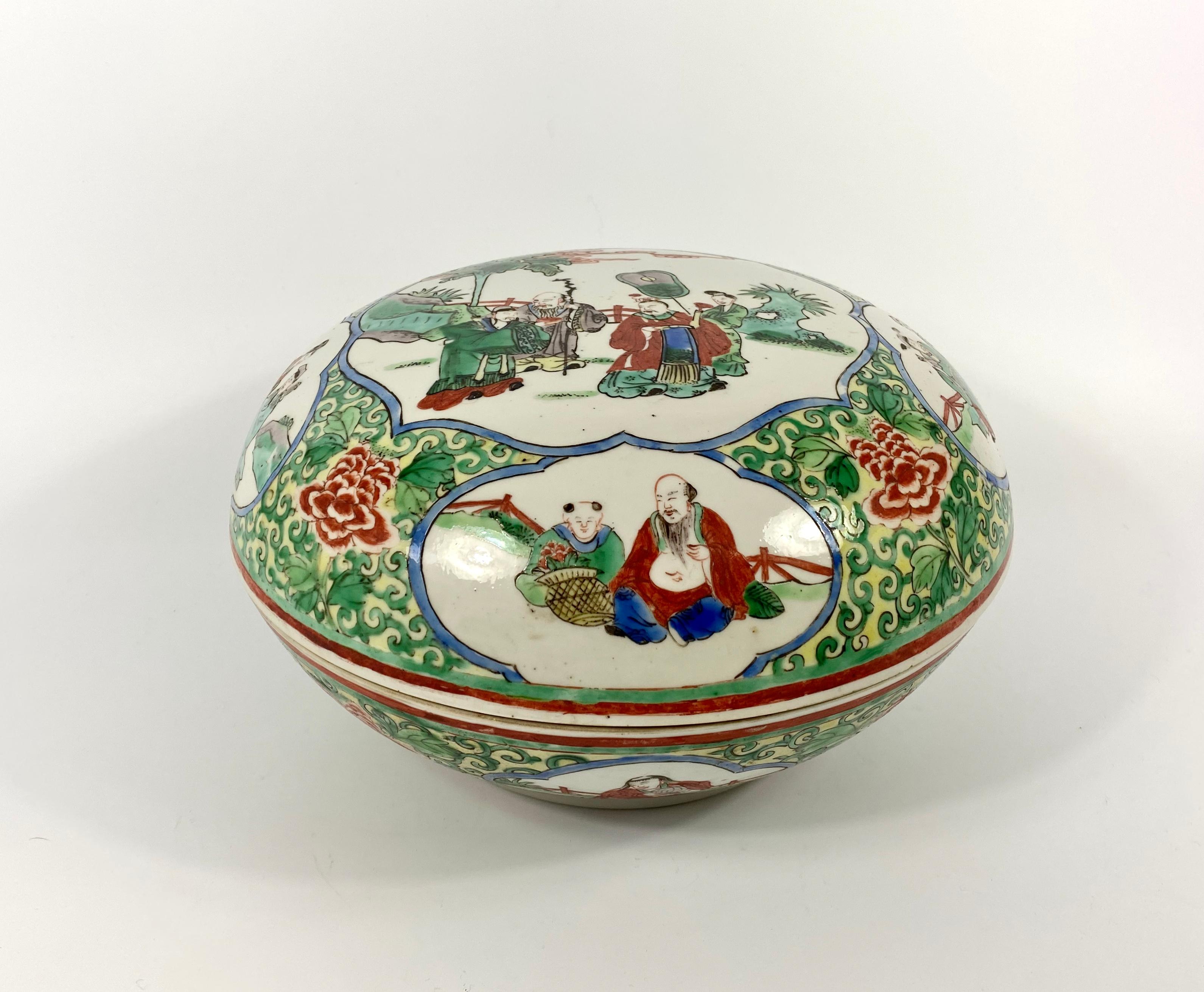 Chinese porcelain box and cover of large size, circa 1900. Qing Dynasty. Hand painted to the cover in wucai or famille verte enamels with panels containing the Immortals in garden settings. All upon a dense ground of green scrollwork and flower