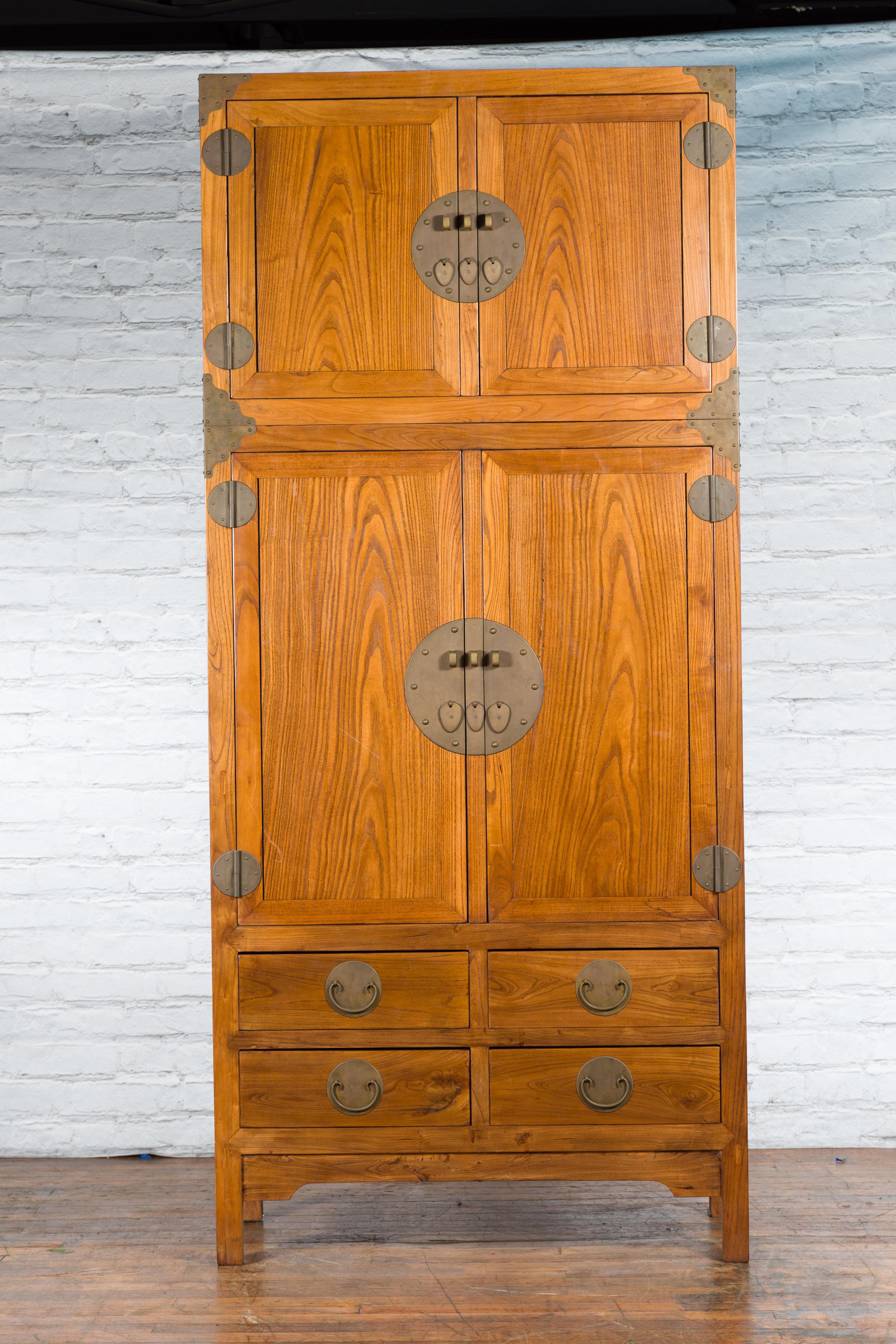 A tall Chinese Qing Dynasty period compound cabinet from the early 19th century made of oakwood and adorned with brass hardware. Created in China during the early years of the 19th century, this large compound wardrobe features a small upper cabinet