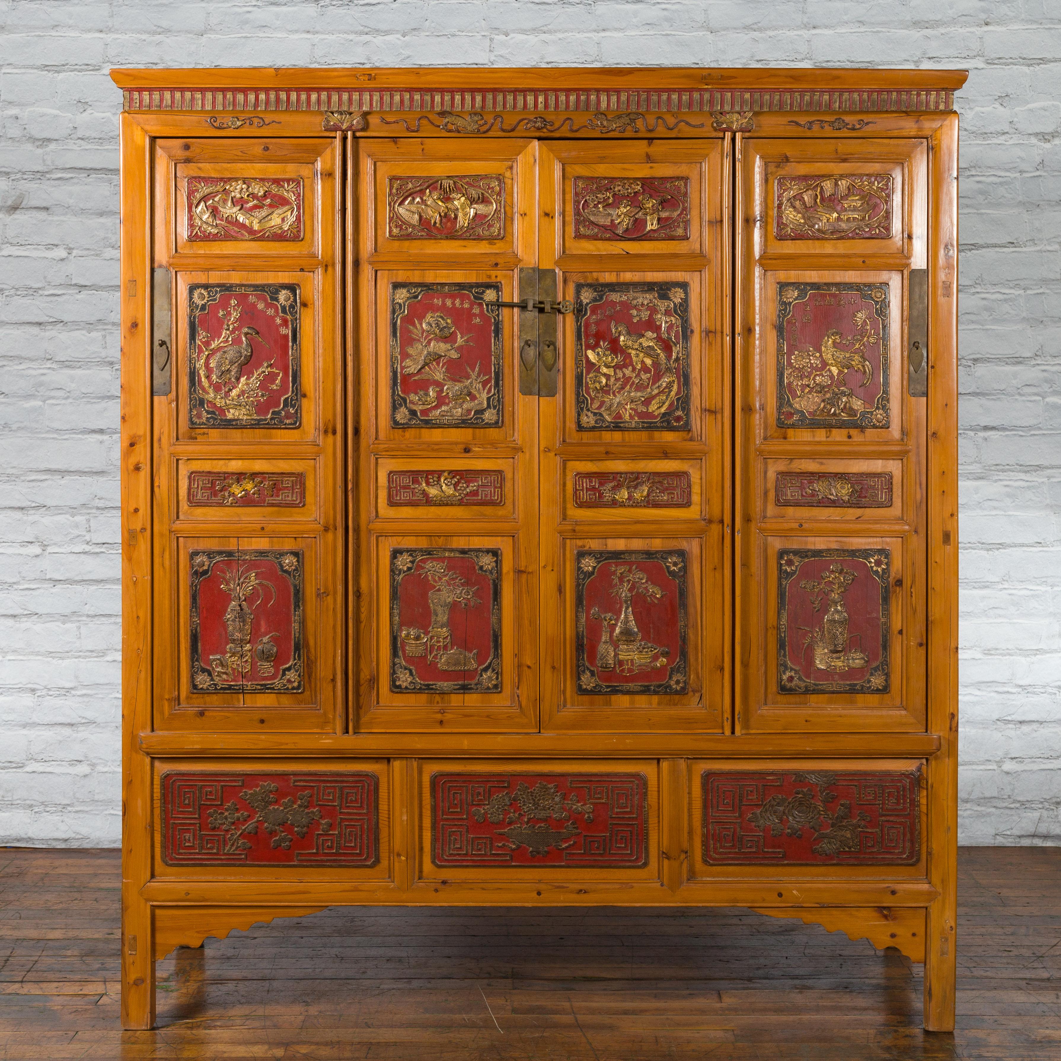A Chinese Qing Dynasty period wide and large cabinet from the 19th century, with hand-carved and gilt panels. Created in China during the Qing Dynasty, this large and wide cabinet features a carved cornice sitting above four doors, adorned with