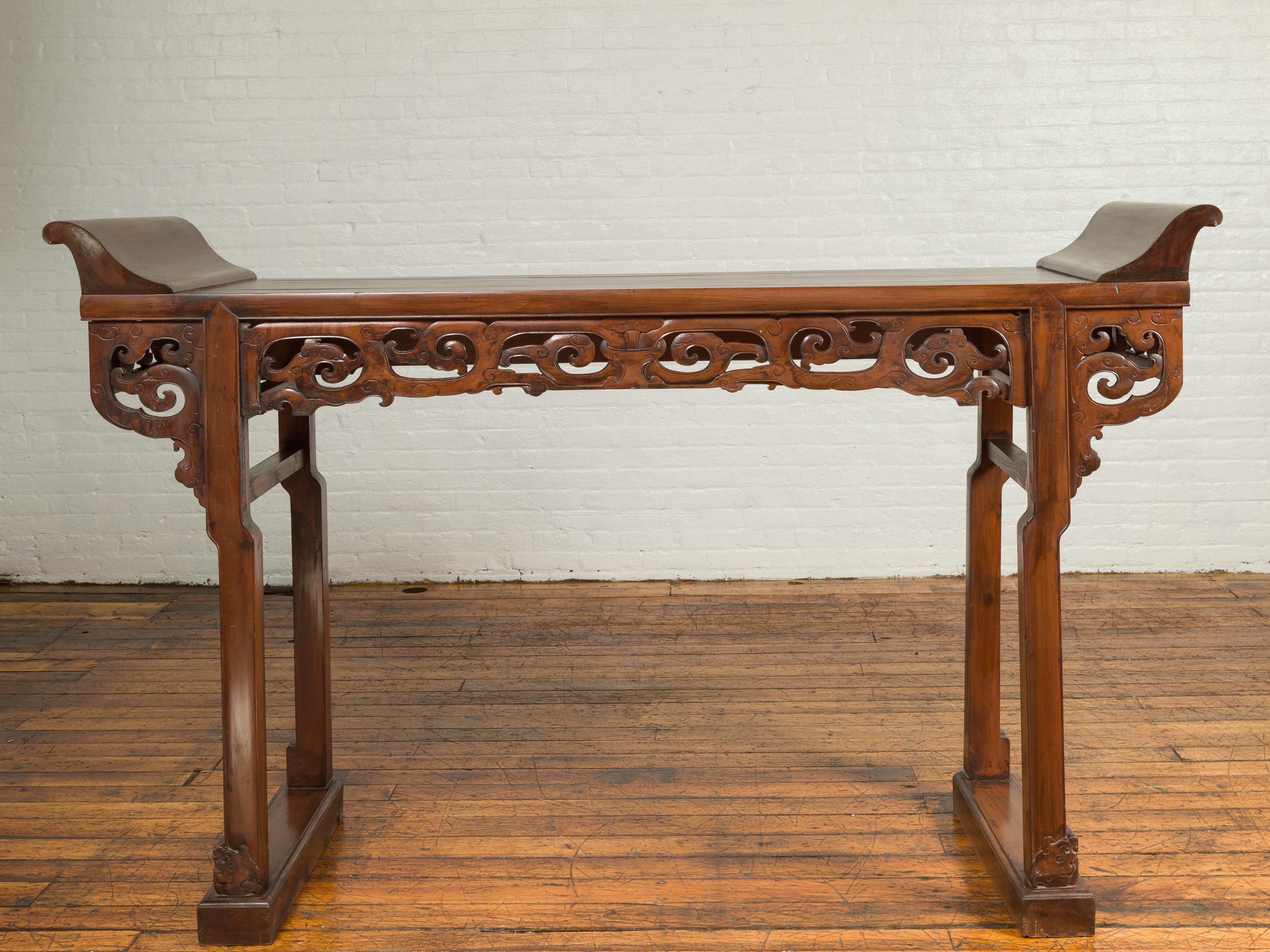 A Chinese Qing dynasty period large altar console table from the 19th century, with everted flanges and carved frieze. Born in China during the 19th century, this Qing altar console table features a rectangular planked top flanked with everted