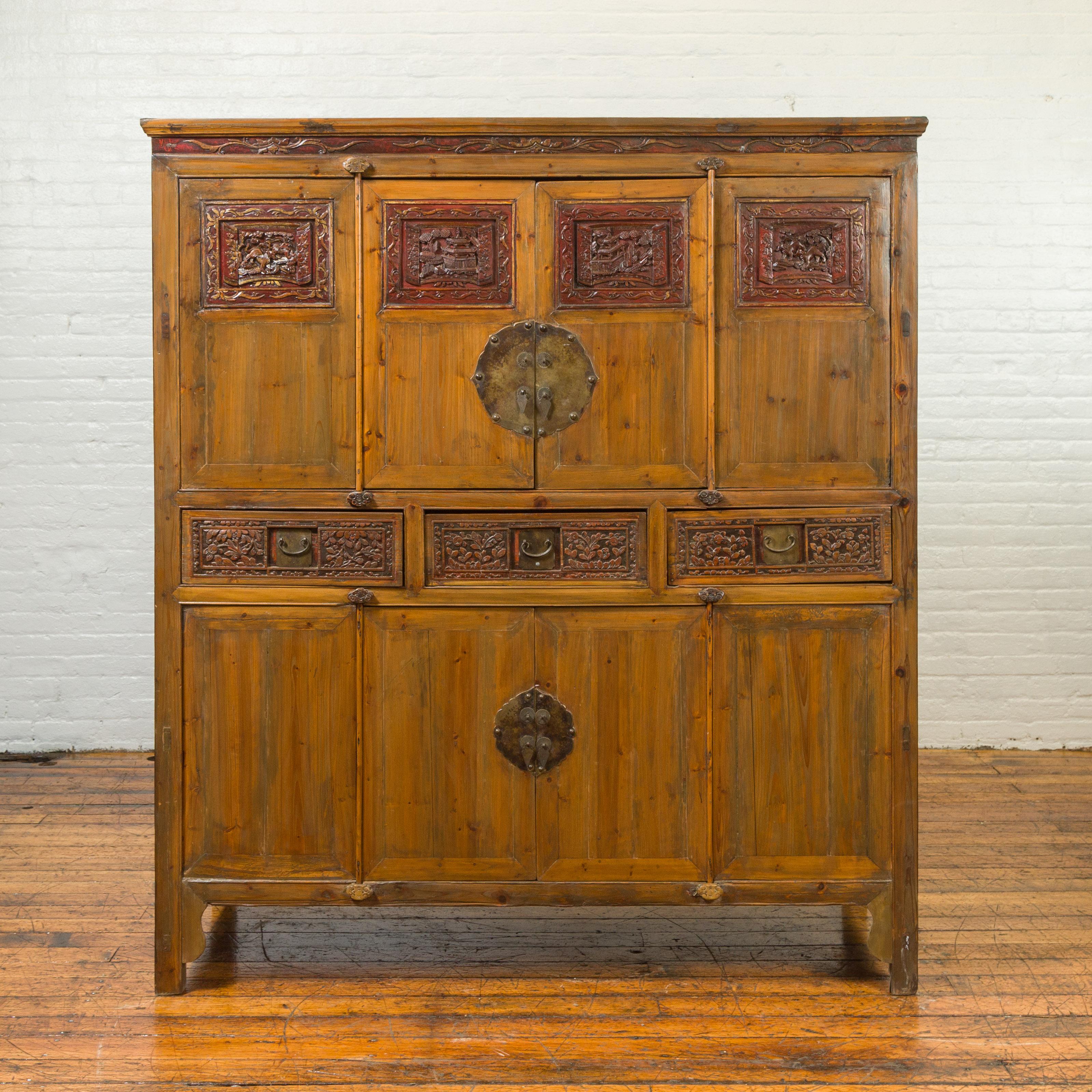 Grande armoire chinoise en bois d'orme de la dynastie Qing du XIXe siècle, avec des panneaux sculptés à la main, des accents laqués rouges et des ferrures en bronze. Créée en Chine au XIXe siècle, cette armoire en orme présente une fine corniche