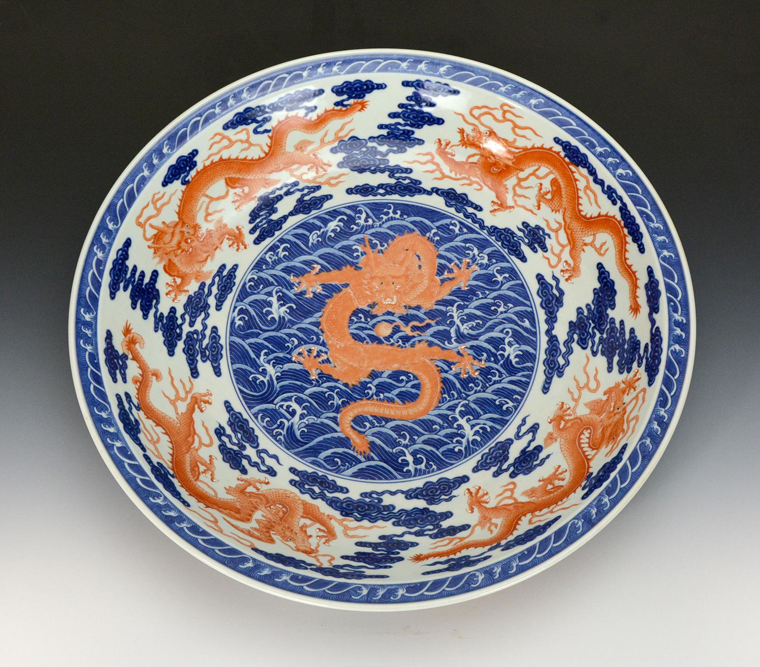 A beautifully hand painted Chinese blue and white charger plate in the highest standard and style of Qing Qianlong period. A large medallion in the center, formed with blue ocean waves. Above a the waves, an outstanding forward facing coral red
