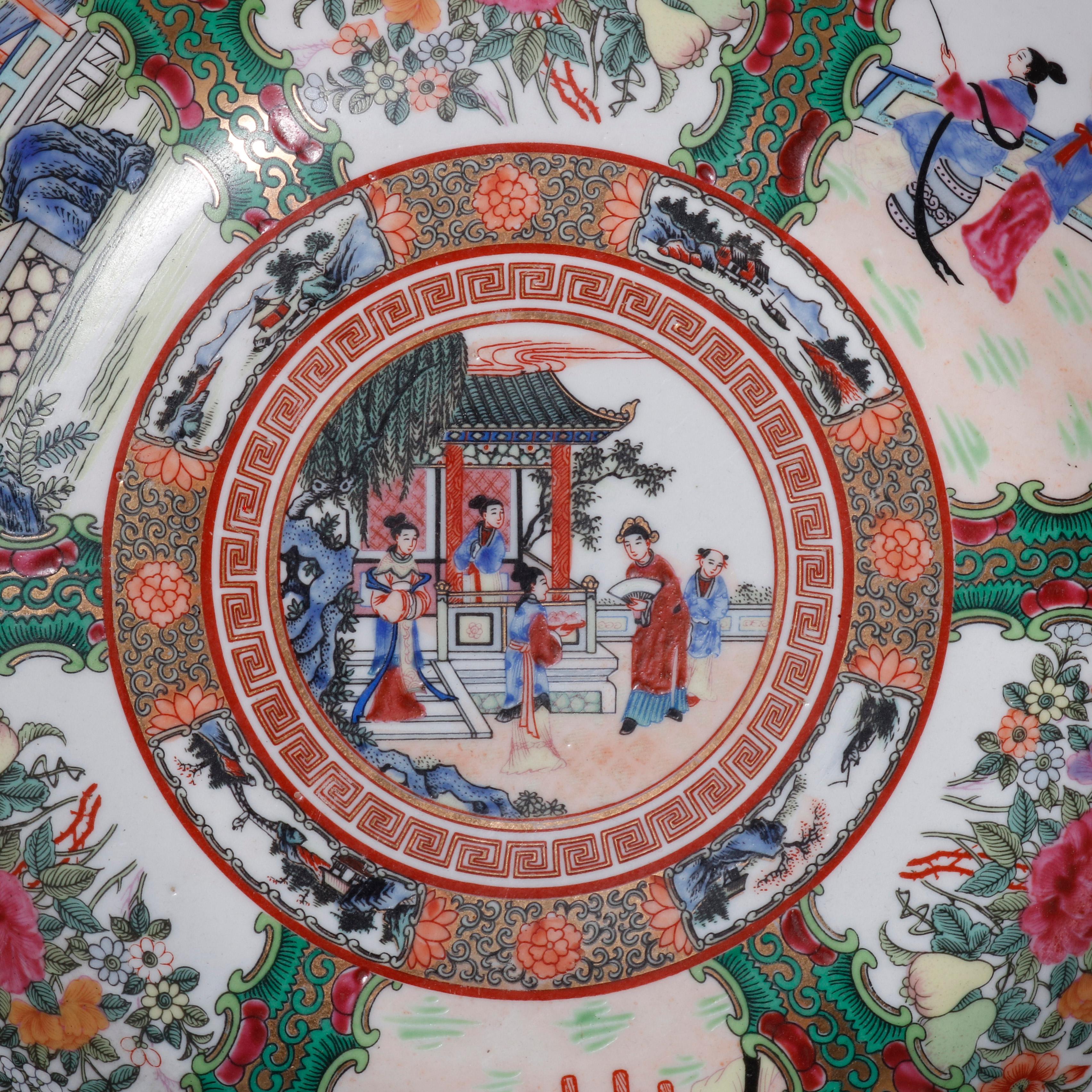 A large Chinese Rose Medallion porcelain center bowl offers hand painted enameled genre and garden reserves including figures, birds, animals, flowers, and pagoda structures, bordered with foliate elements and Greek key banding, gilt highlights