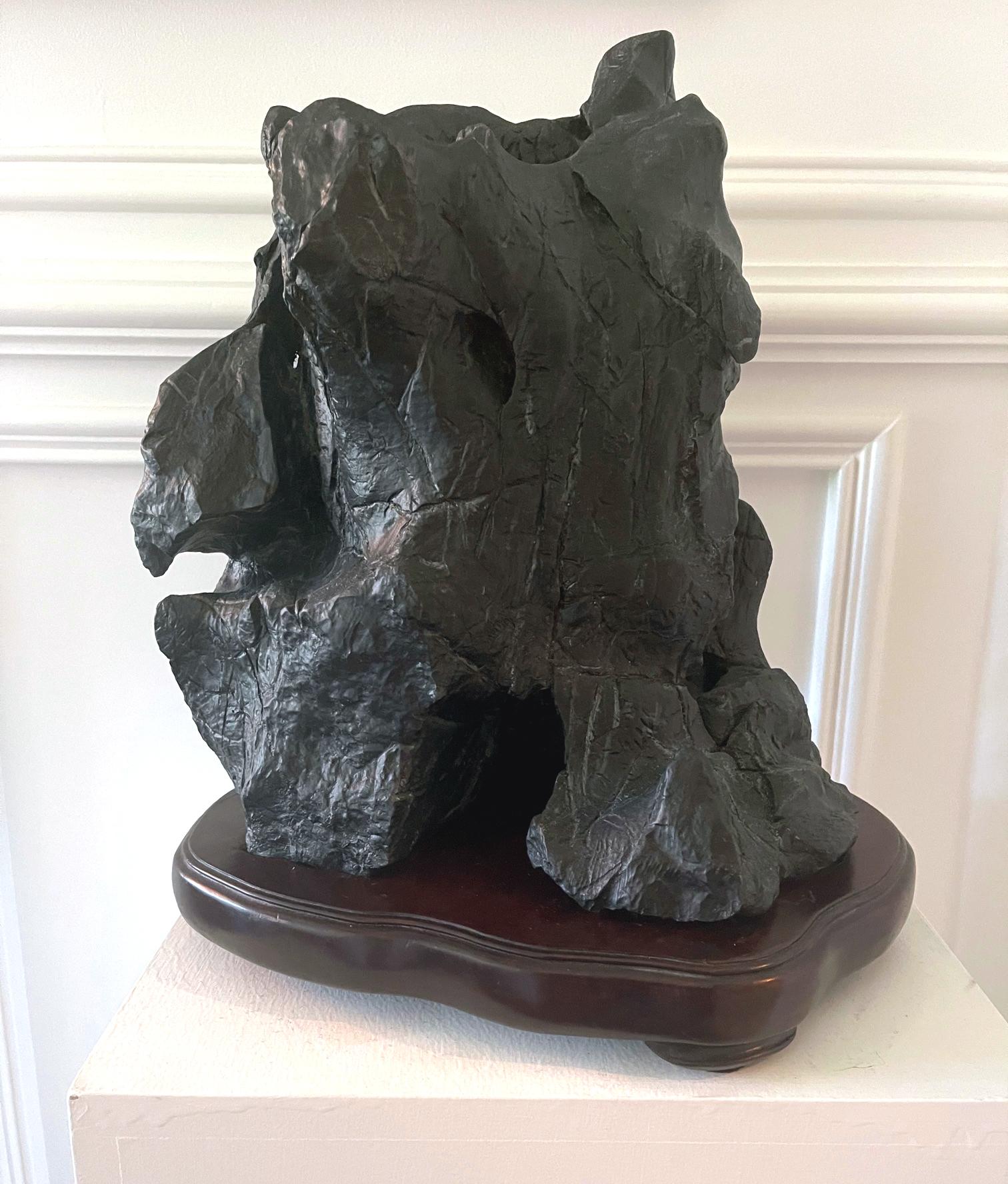 An impressive Chinese scholar stones (also known as Gong Shi, meditation stone and spirit rock) on display wood stand circa late 19th century to early 20th century. This mountain-form Lingbi stone features a nearly complete black surface with very