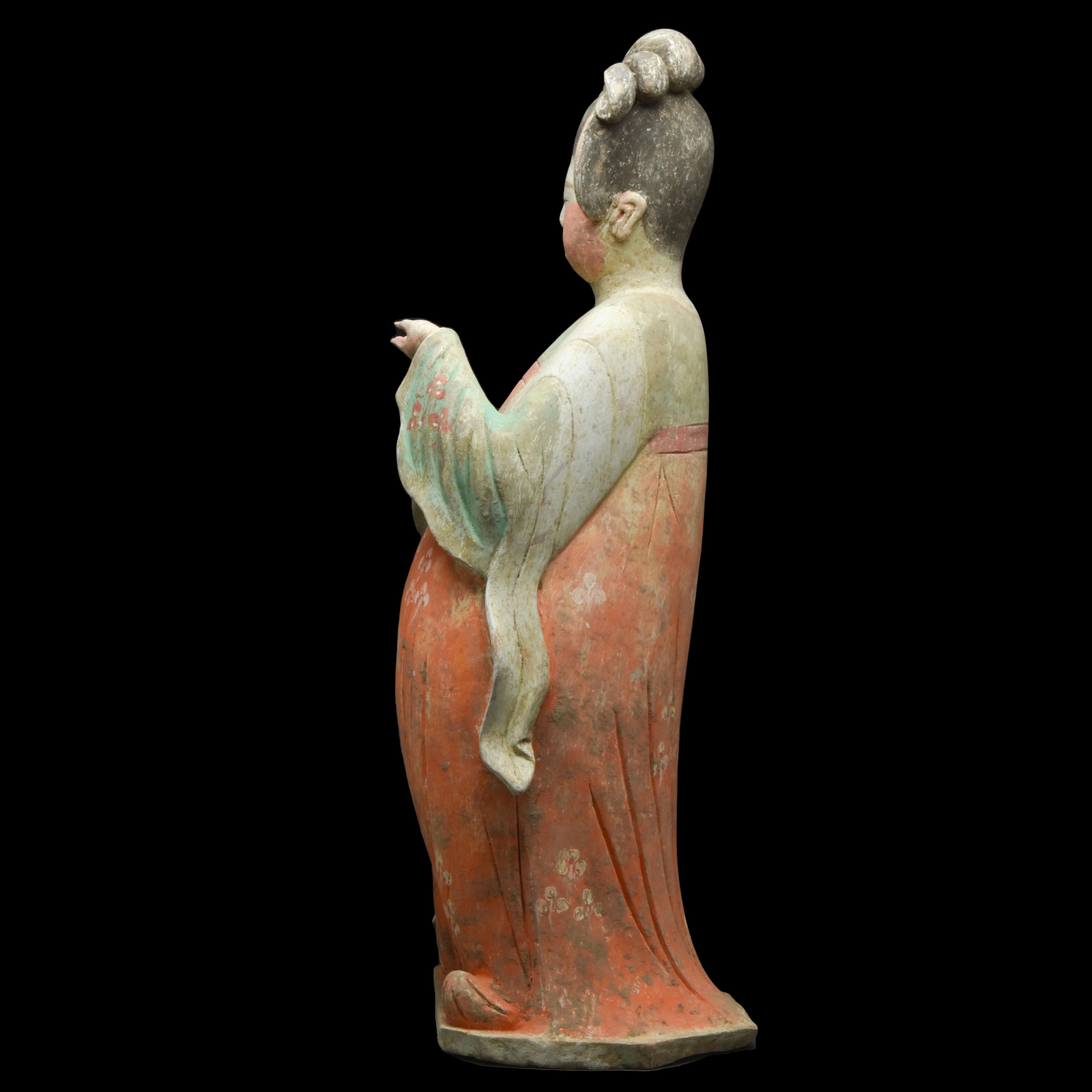 A ceramic figurine known as the 'Fat Lady.' Crafted with meticulous attention to detail, this figure stands in a graceful pose, her curvaceous body swayed to the side. Resting upon an integral flat base, she is adorned in a flowing, long robe that