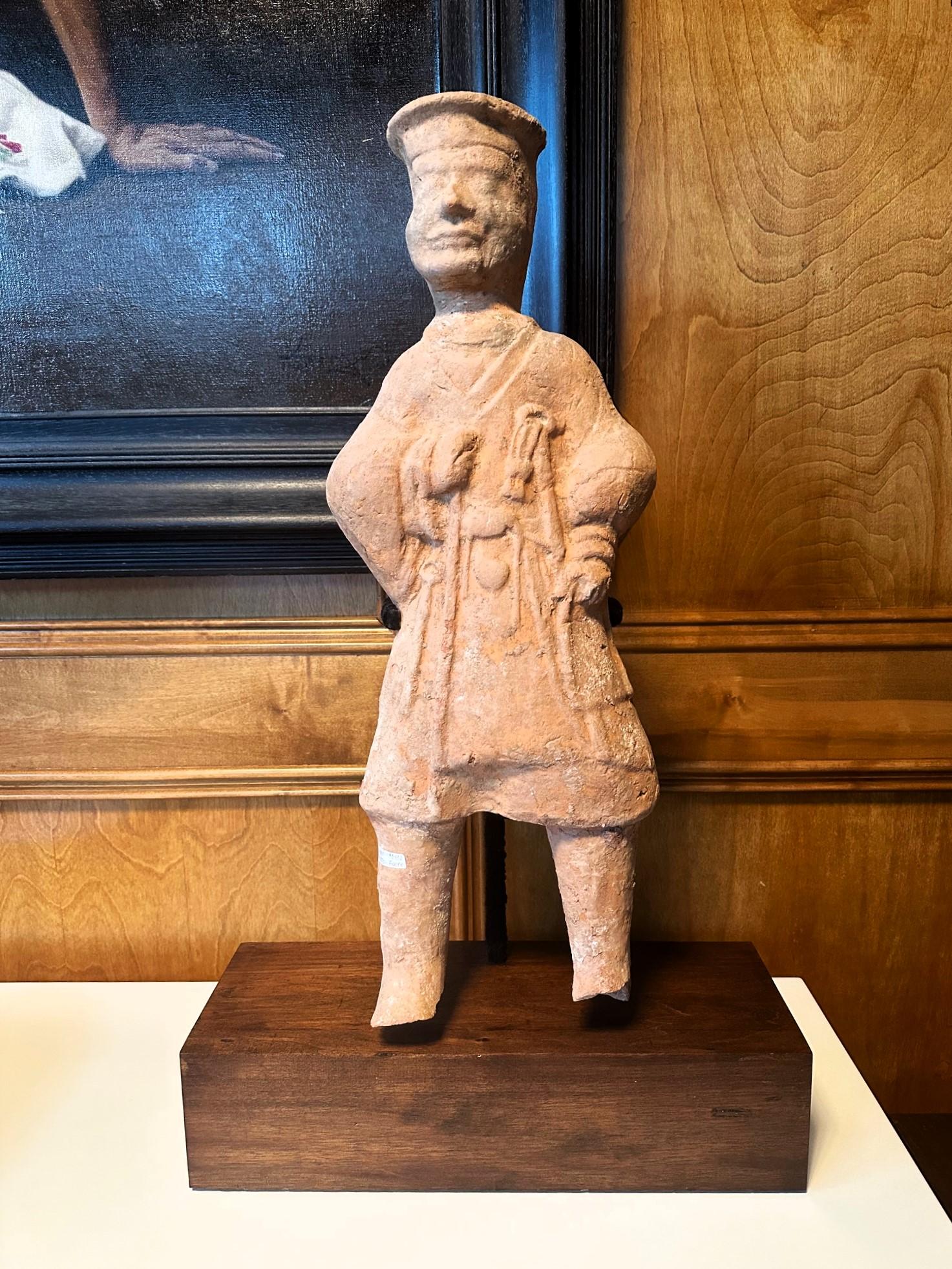 Figurine funéraire chinoise en terre cuite (Ni Yong) de la dynastie des Han de l'Est (25-220 ap. J.-C.), probablement originaire de la région de l'actuel Sichuan. Elle semble représenter un palefrenier avec des vêtements et un harnais à la main.