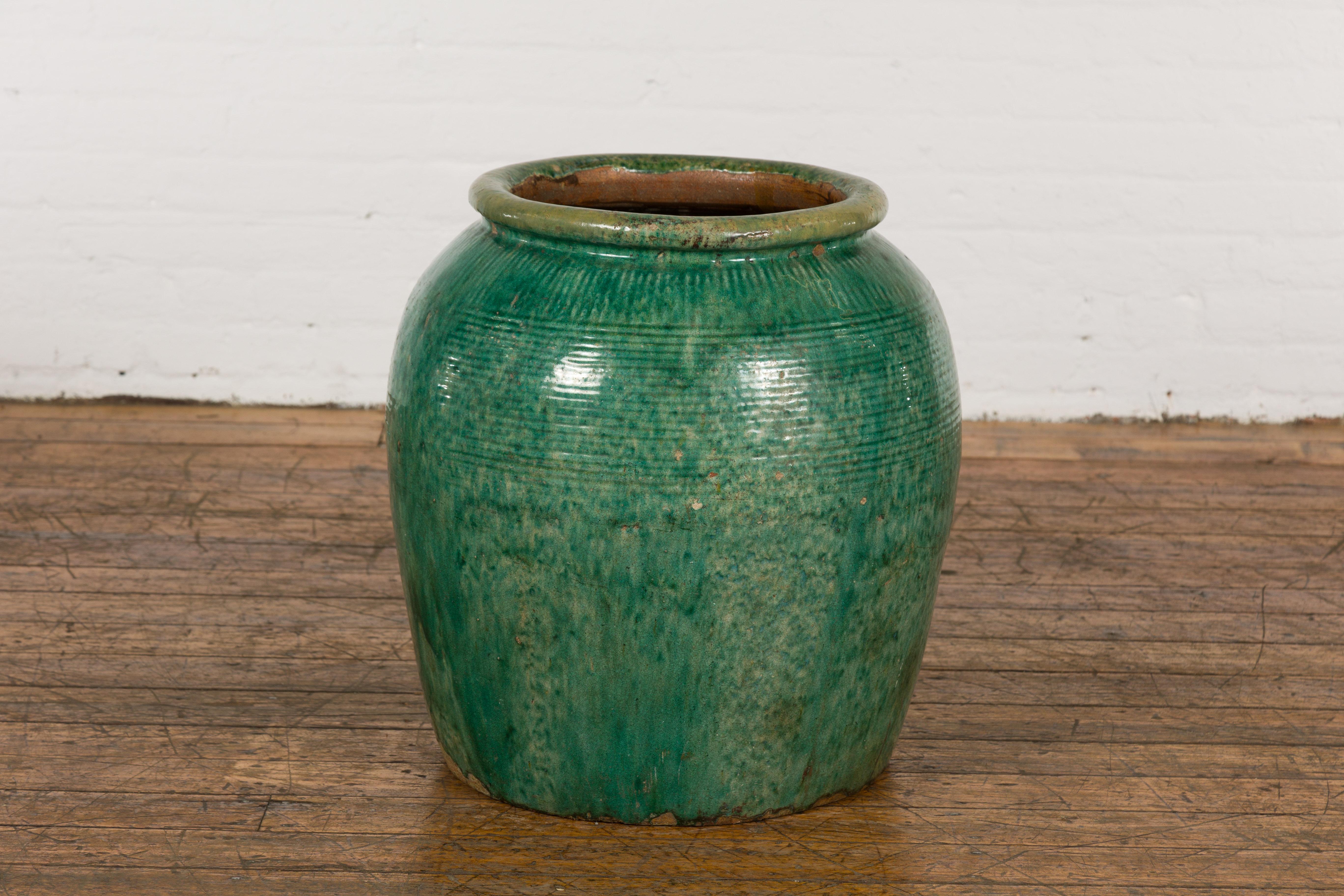 A large vintage Chinese green glazed water vessel perfect to be used as a garden planter. Hailing from the vintage era, this Chinese water vessel is a captivating blend of traditional craftsmanship and modern utility. With its vibrant green glaze,