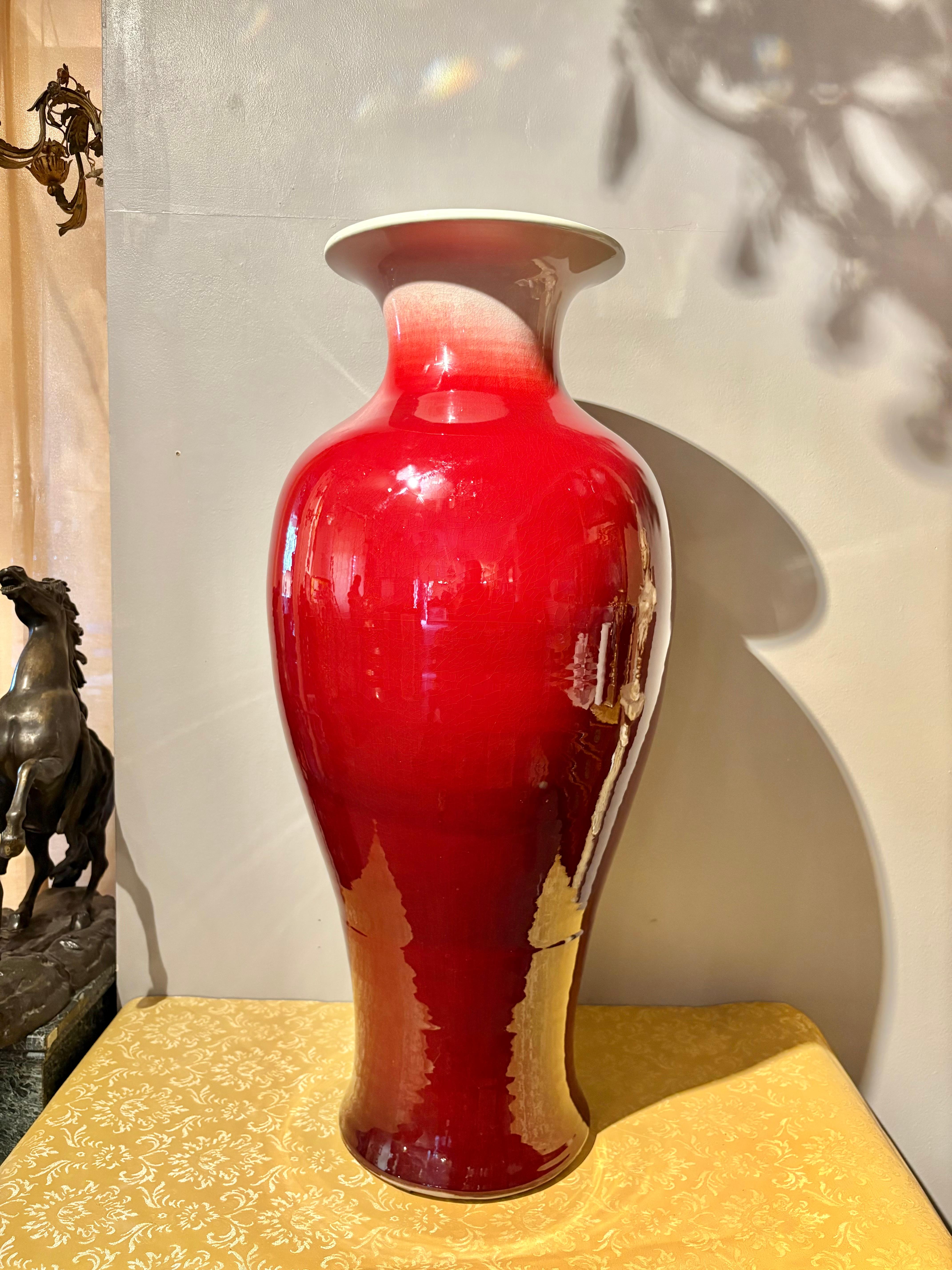 Questo imponente vaso cinese vintage, realizzato nel XX secolo, è un ottimo esempio della rinomata tecnica di smaltatura Sang de Boeuf (nota anche come sangue di bue). Il pezzo è alto ben 97 cm (38,2 pollici) e ha un diametro di 45 cm (17,7