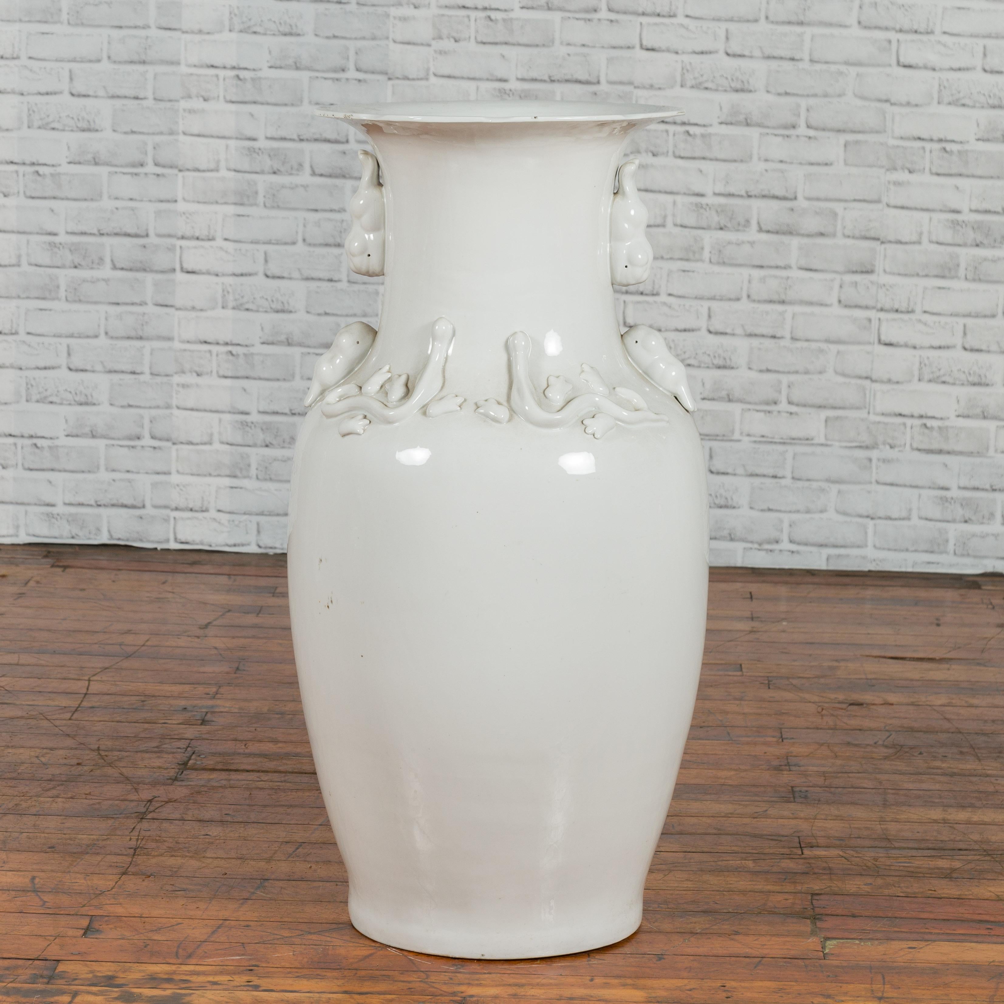 A large Chinese vintage white porcelain palace vase from the mid-20th century, with petite decorative motifs. Created in China during the midcentury period, this porcelain vase features a tall neck with petite decorative motifs, supporting a flaring