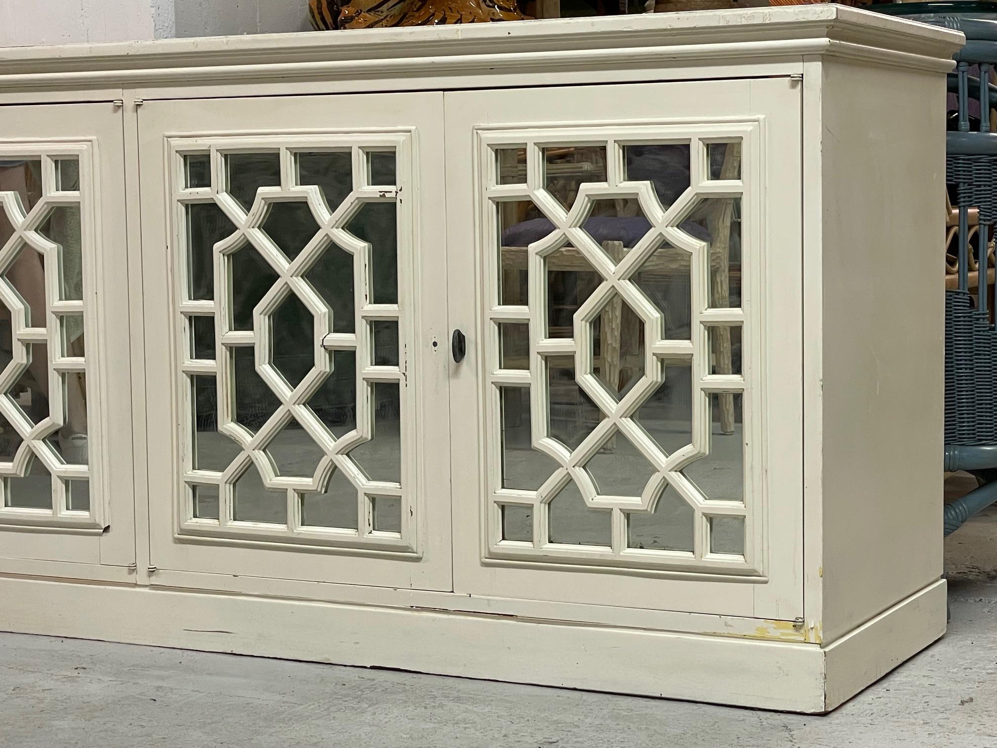 Large solid wood credenza features triple double door storage sections. Mirrored front doors overlaid in Asian style fretwork. Good vintage condition with scuffs to the original finish. Structurally sound and drawers doors operate smoothly. Missing
