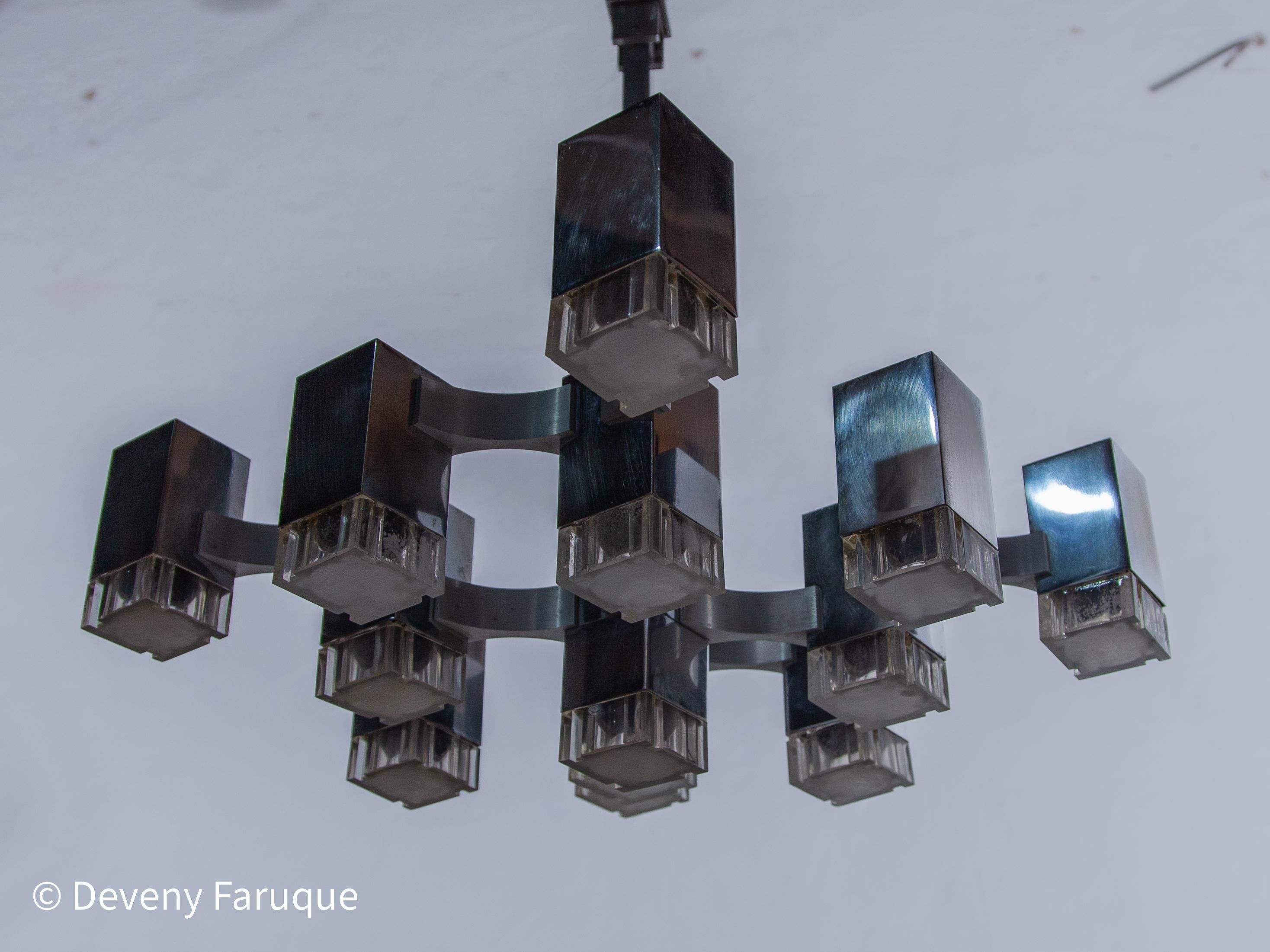 Il grande lampadario cromato Midcentury Modern Graphic è composto da 17 luci che irradiano una luce suggestiva. La struttura è composta da 17 cubi di metallo cromato con cubi di perspex collegati tra loro da linee di alluminio massiccio. Un