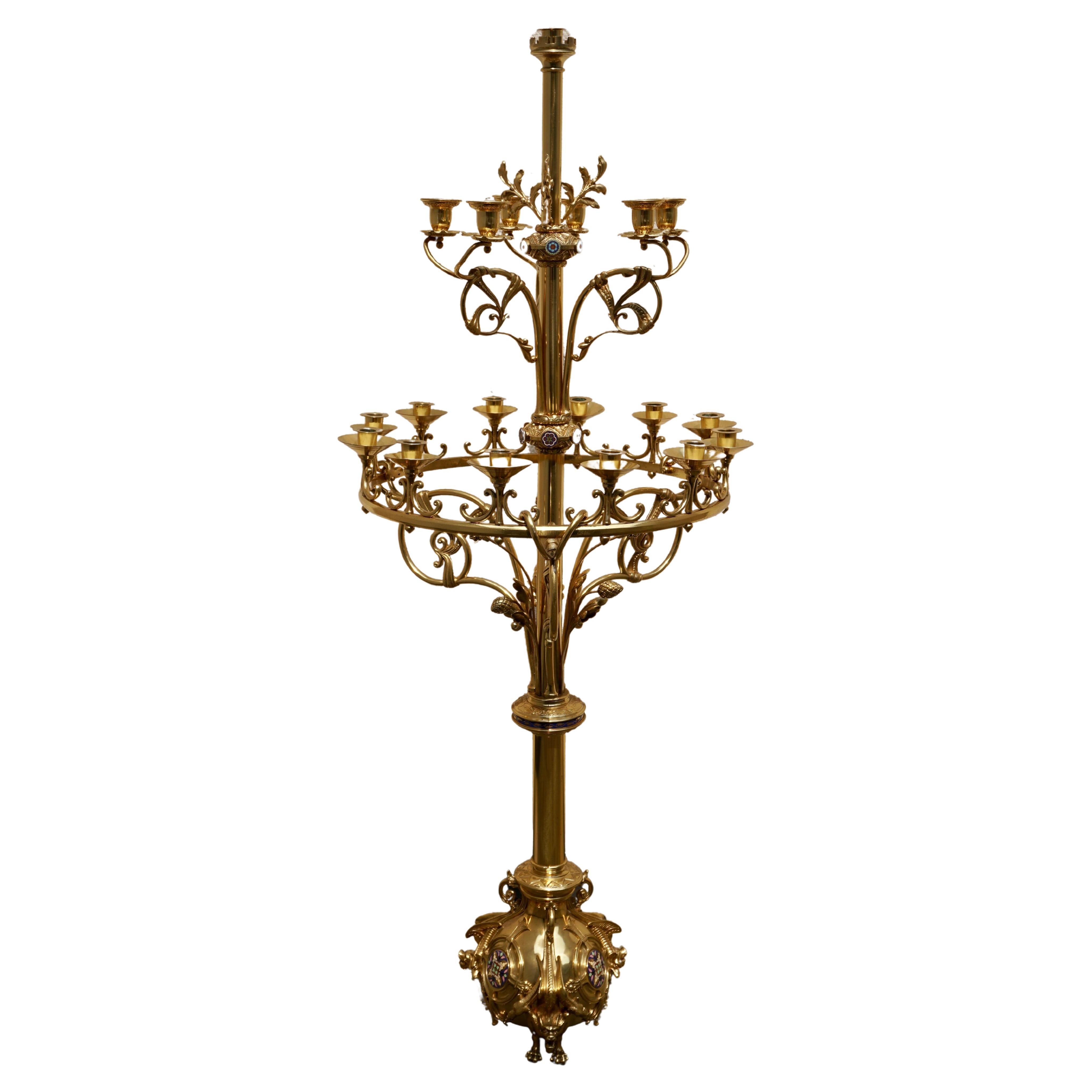 Brass and enamel multi-light standing candelabra in the Gothic style. The foot is bulbous scroll pattern with enamelled cartouches sitting on three mythical beasts. The candle holders are on two tiers with scroll patterns supporting.This is a