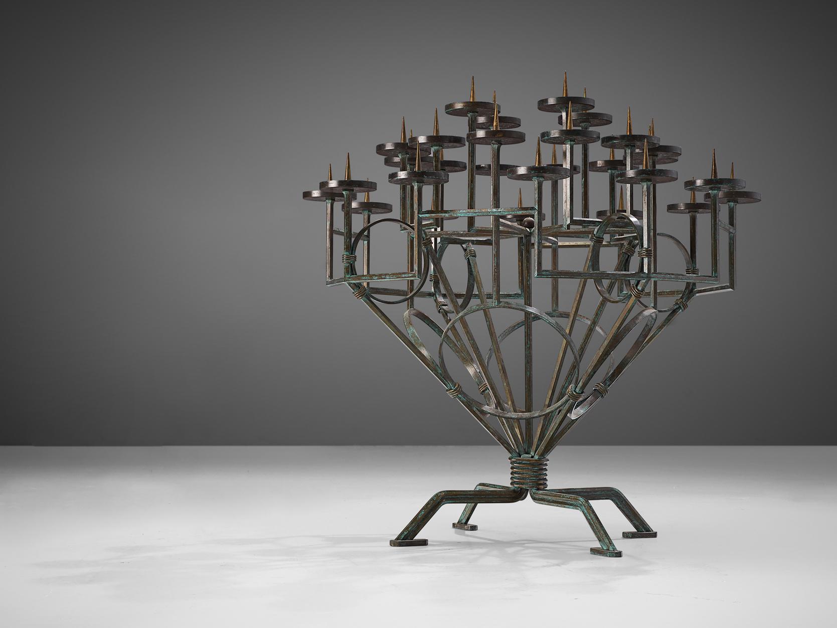 Candleholder, bronzed iron, Europe, early 20th century.

Large size candlebra that features a multitiered spread of candle holders organized in a circular manner from a central frame. The general color of these very decorative elements is green as