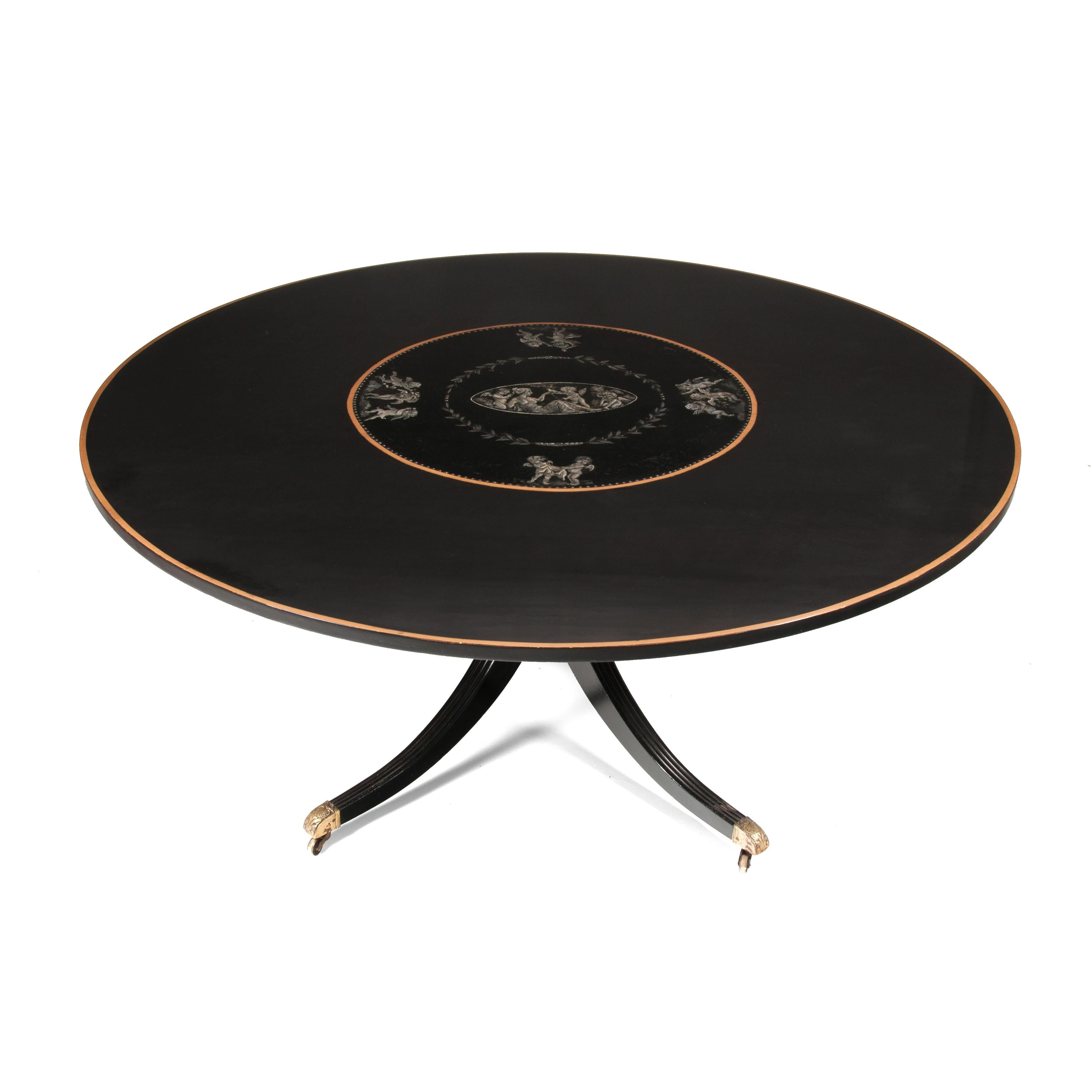 A large 5 1/2 feet diameter circular mid-20th century ebonized, gilt and painted Hollywood Regency style dining table on central splay base circa 1960s-1970s. 

English, circa 1960s-1970s.

The large 66 inch diameter top having a hand painted