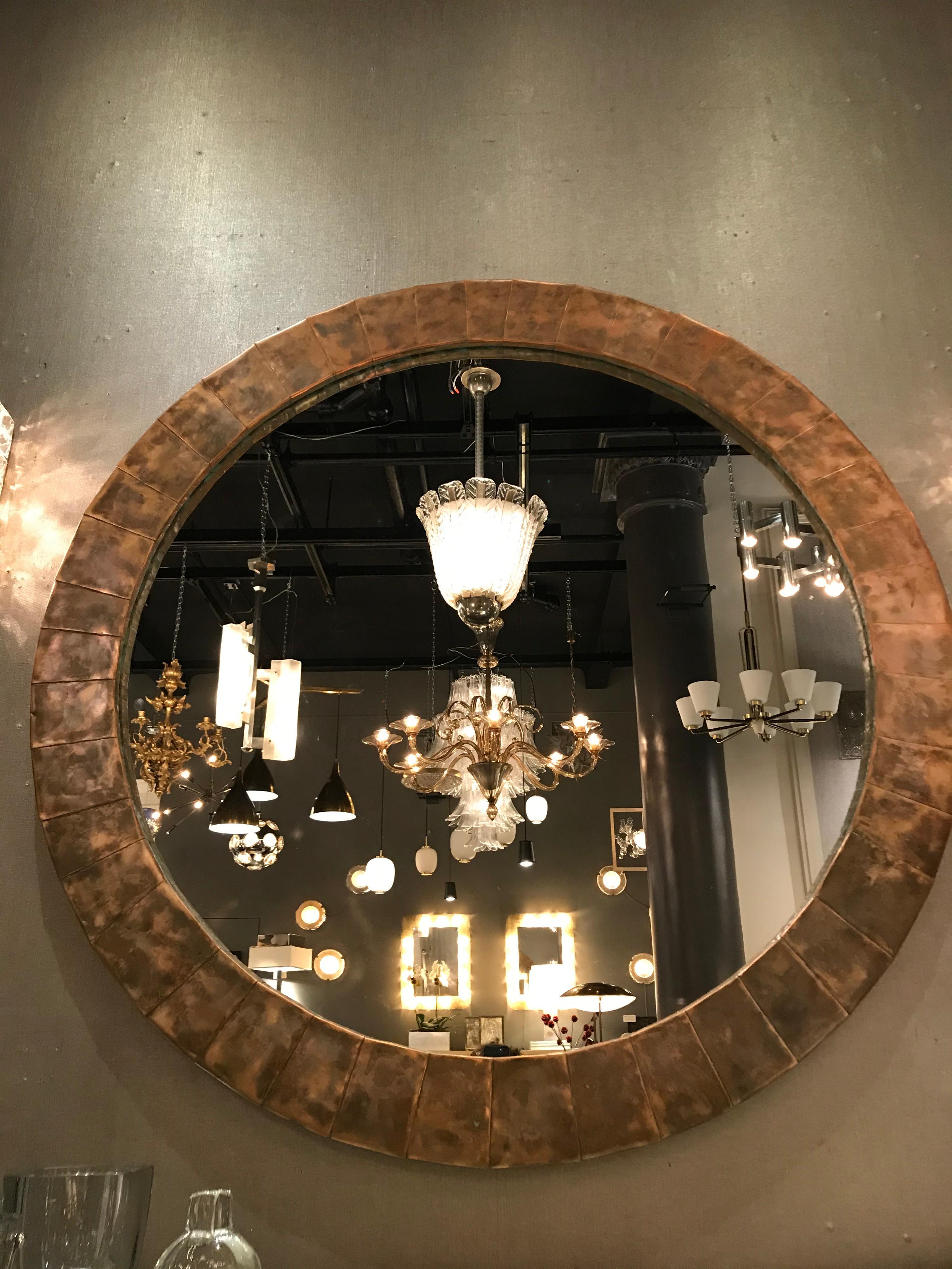 Oversized circular mirror surrounded by a naturally patinated copper frame.
  