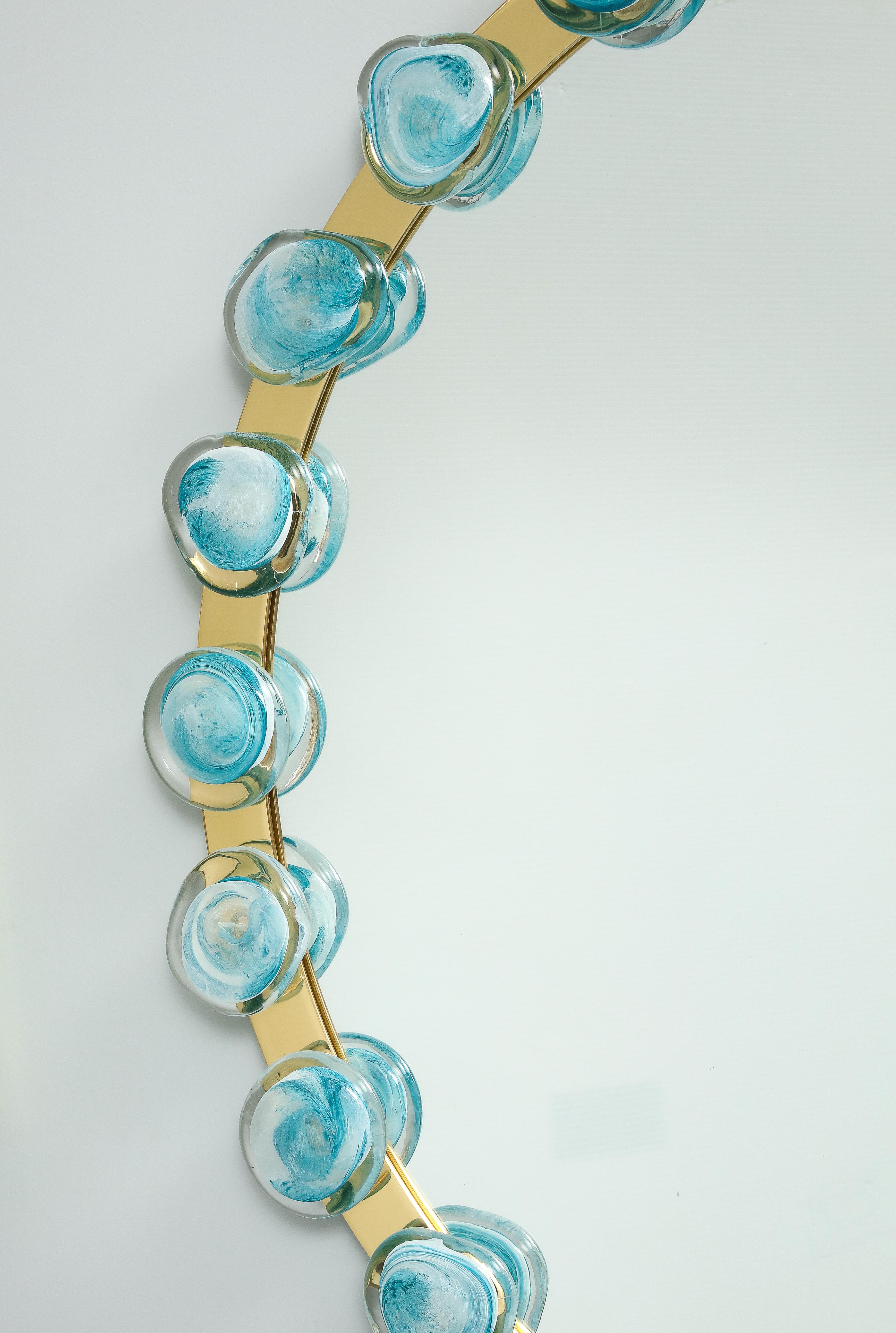 This mirror is unique as it has been designed and made by an Italian artisan. The mirror is encircled with gold brass with hand blown blue  Murano ornements fixed on the base..