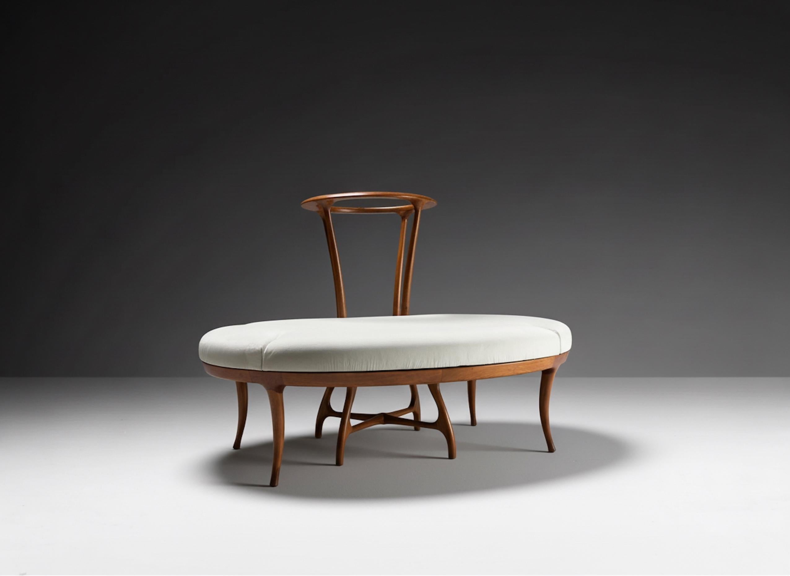 The circular sofa features an elegant design in the Italian mid-century style, featuring an oval base with a warm amber-toned wood frame. The slender, curved legs, joined by a central support, provide stability and a sculptural touch. The seat is