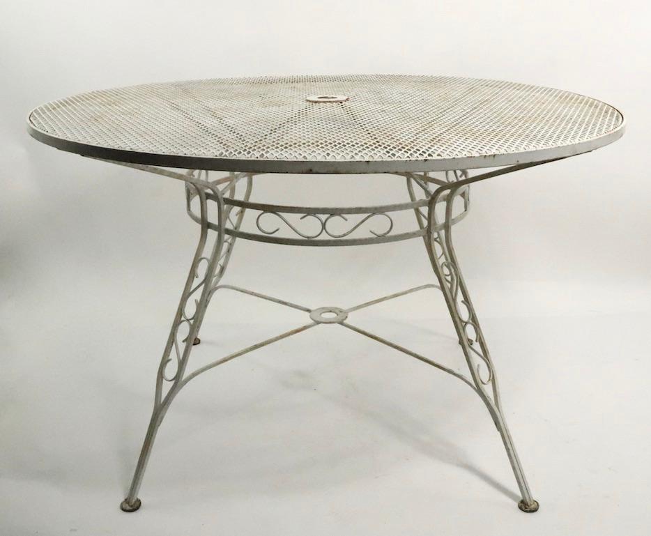 Extraordinary wrought iron and metal mesh dining table having a circular top, and decorative splayed wrought iron legs. This table is unusually large and substantial, perfect for patio, garden, sunroom or poolside use. This example is in very fine