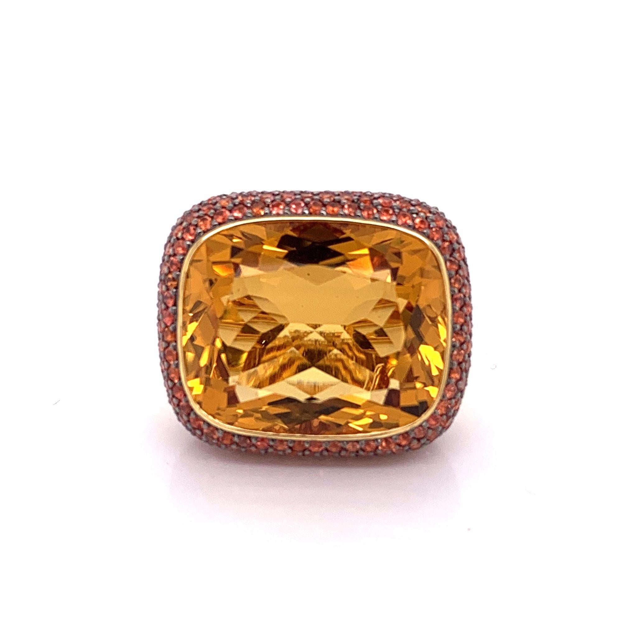 A bold ring featuring a luscious 26.22 carat natural citrine. The massive gemstone has a pleasantly even orange color and a beautiful cut. The rest of the ring is studded with 5.44 carats of orange sapphire which accent the center gemstone. Set in