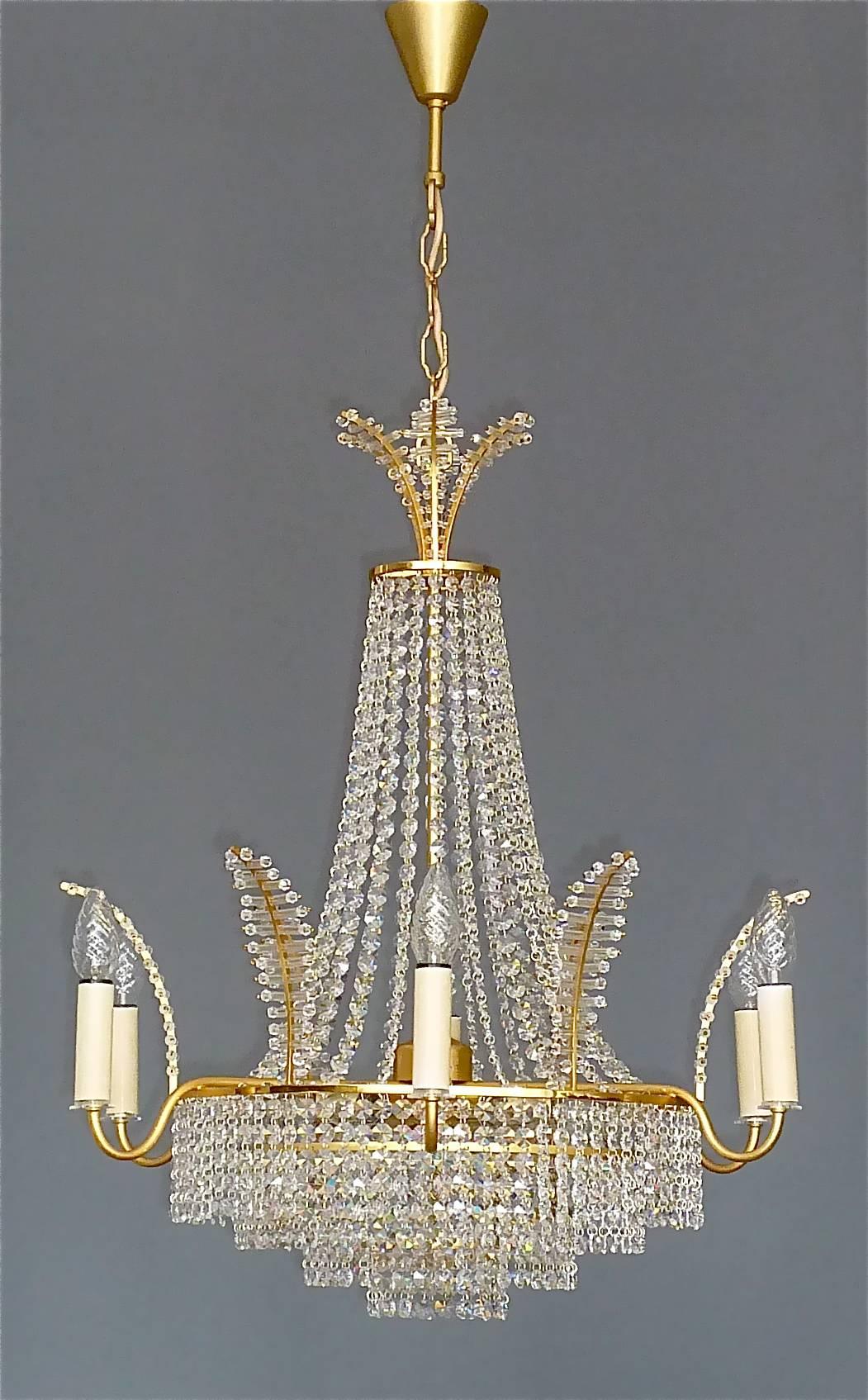 Fine large gilt brass and crystal glass chandelier made by high class lighting company Palwa, Germany, circa 1960. The classical chain-hanging length-adjustable chandelier has four cascading tiers, a palm-leaf crown motif on top and outer rim and