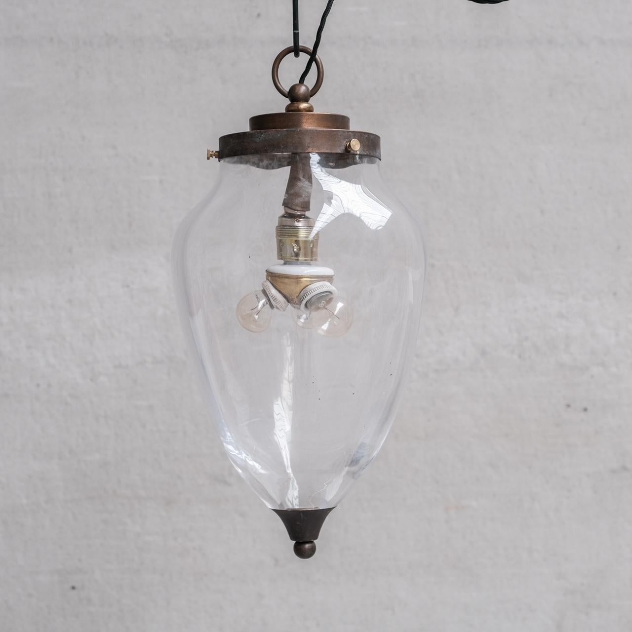 A large clear glass and brass pendant light. 

Holland, c1950s. 

Thick glass, stepped brass gallery, with natural patination. 

Added addition of a period bulb extender option to make it a three bulb light. 

Please note this is a period electrical
