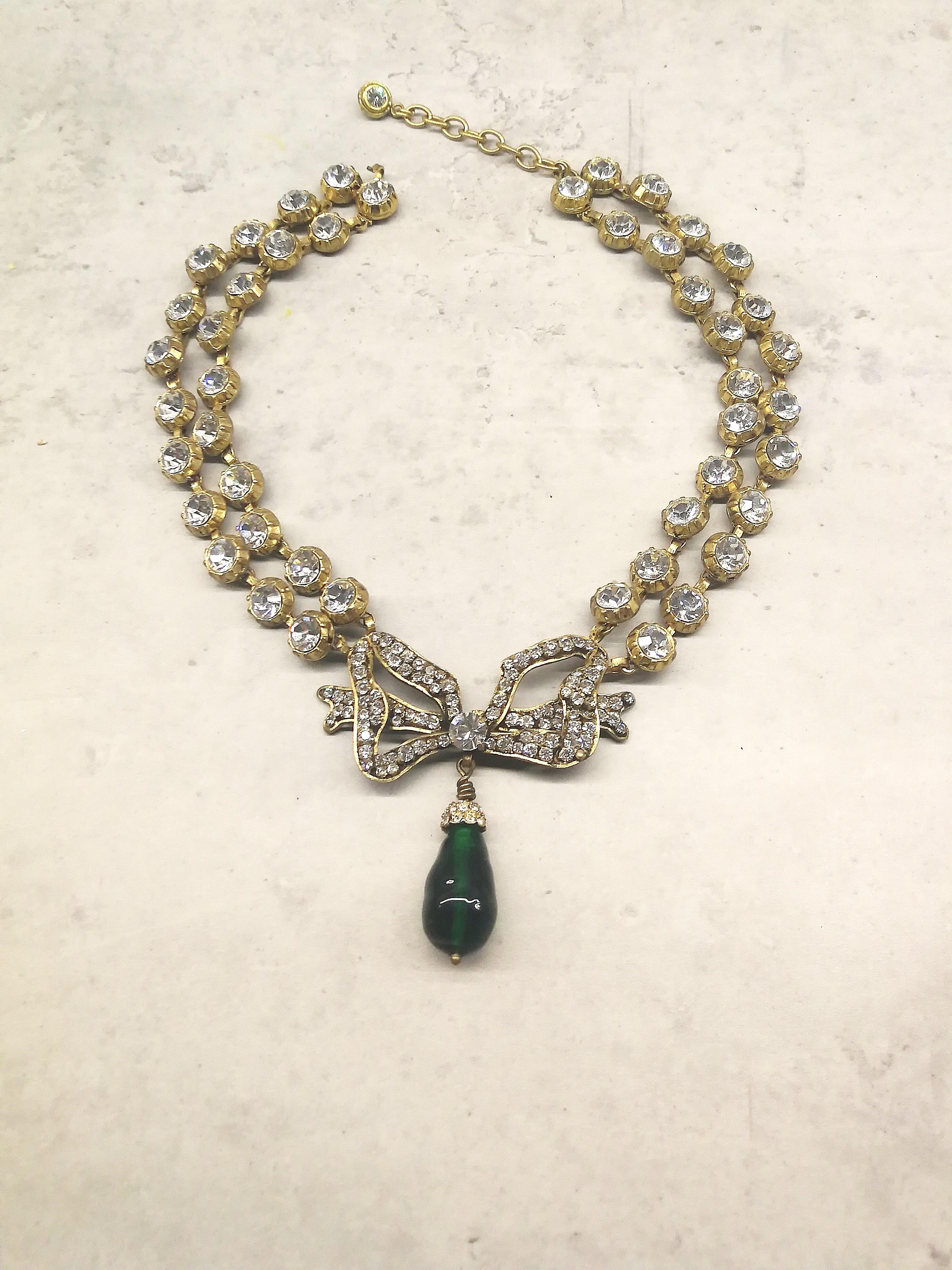 This stunning, classic necklace is made from clear pastes, in gilt metal settings, with a large paste bow as the centrepiece, from which hangs a large emerald poured glass drop. It is a perfect example of the long collaboration between Chanel and