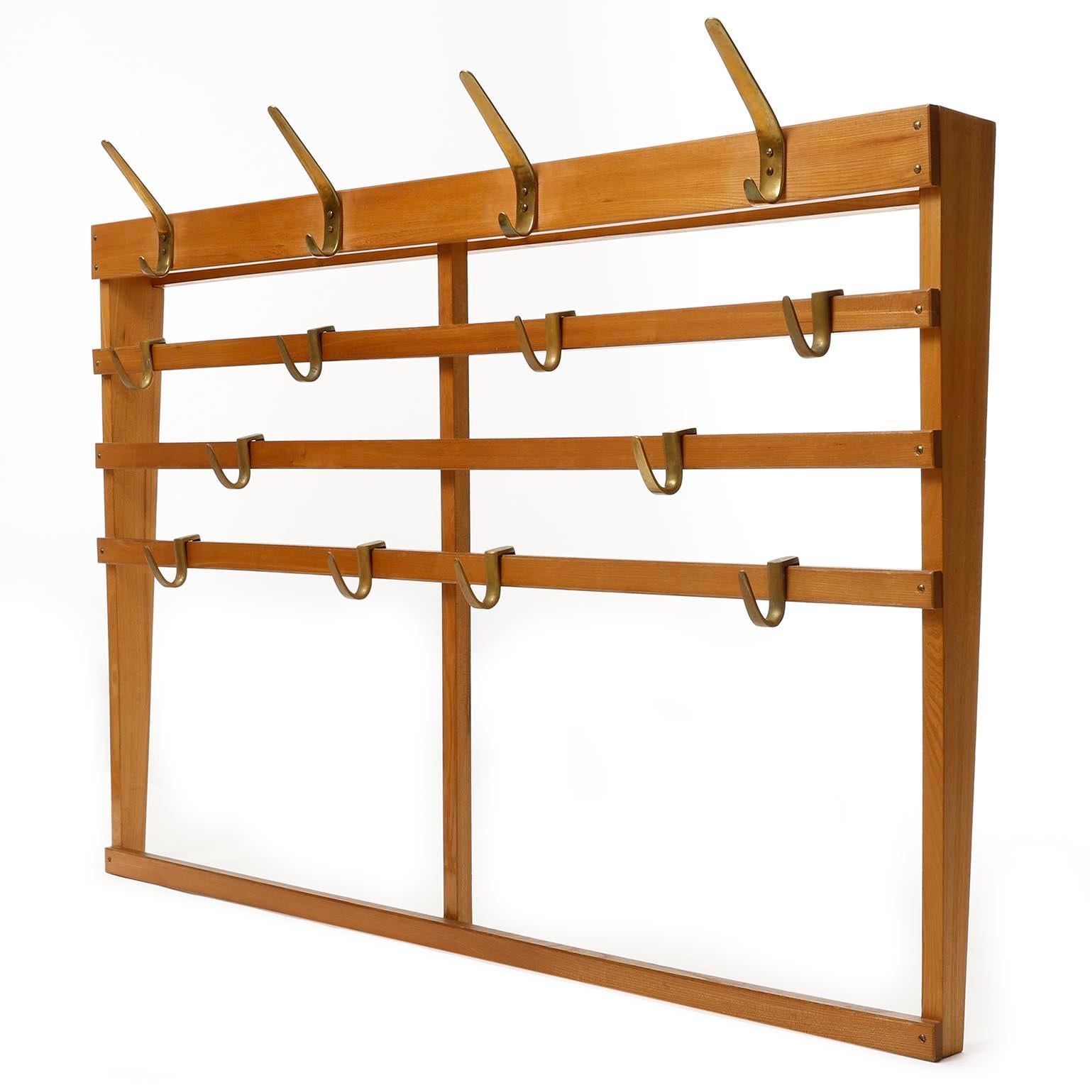 A large wooden coat check with patinated brass hooks manufactured in midcentury, circa 1950.
It consists of a frame made of wood and six polished solid brass hooks with lovely patina.
Five horizontal slats are mounted with patinated brass screws