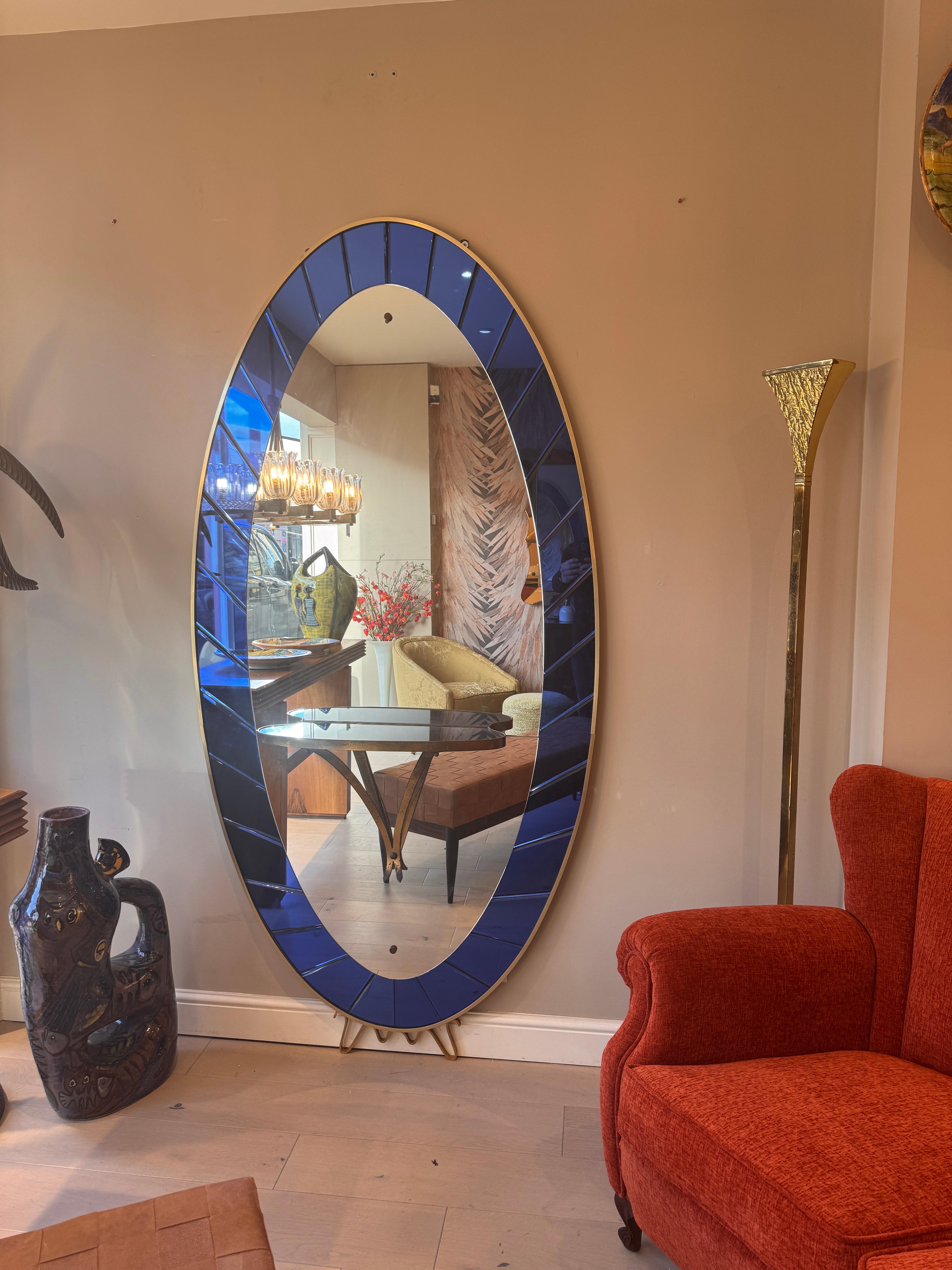 Majestic specchio e consolle di forma ovale con splendidi pannelli in vetro specchiato blu cobalto e cornice in ottone. Nella parte inferiore, una console decorativa in ottone con un piano in vetro blu. 
Progettato e prodotto da Cristal Arte