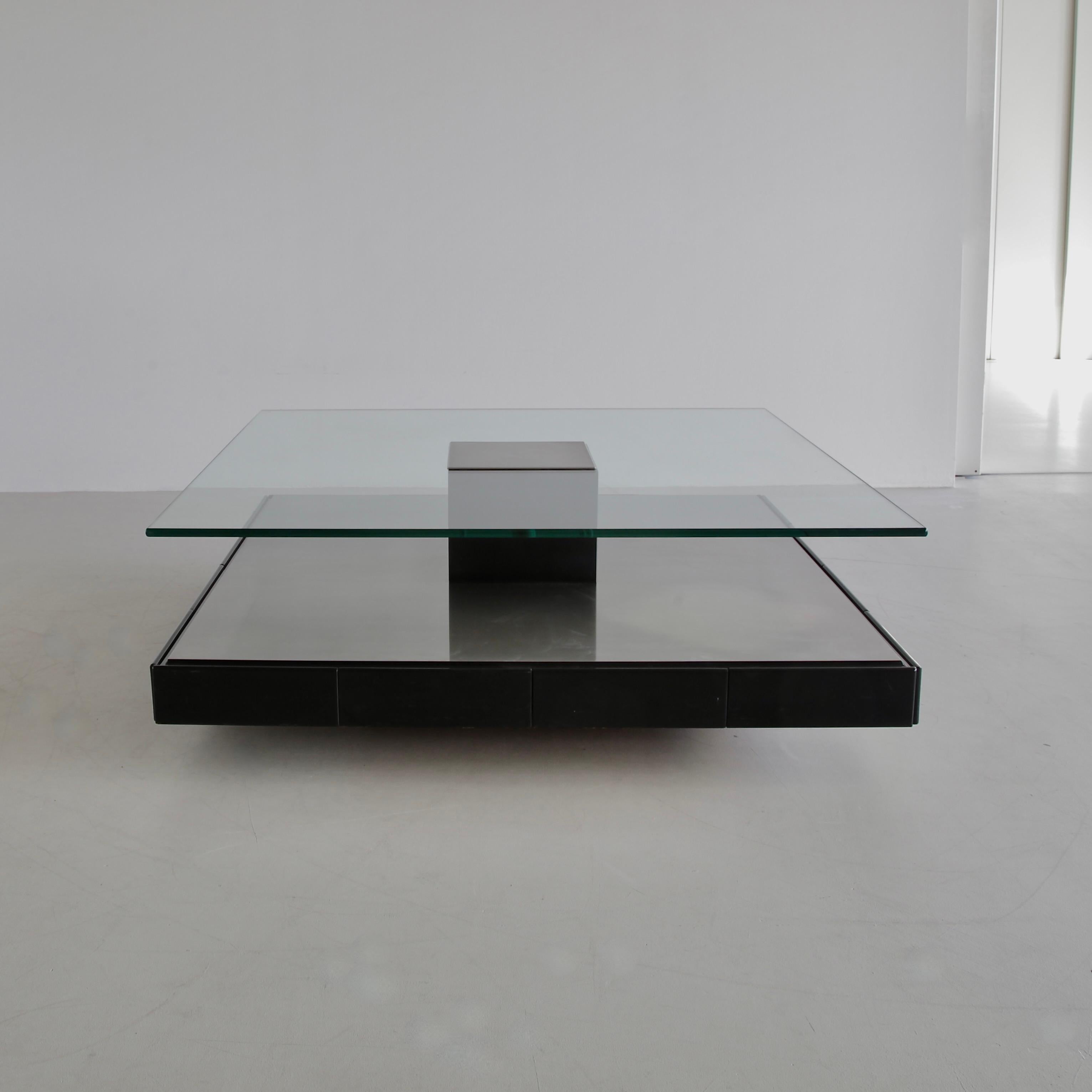 Minimalist coffee table (Tecno T147) with brushed metal base on wood containing eight drawers, thick glass shelf with brushed metal insert. Tecno labels on glass and all drawers. Eight rollers underneath the base for easy manoeuvring. Fantastic