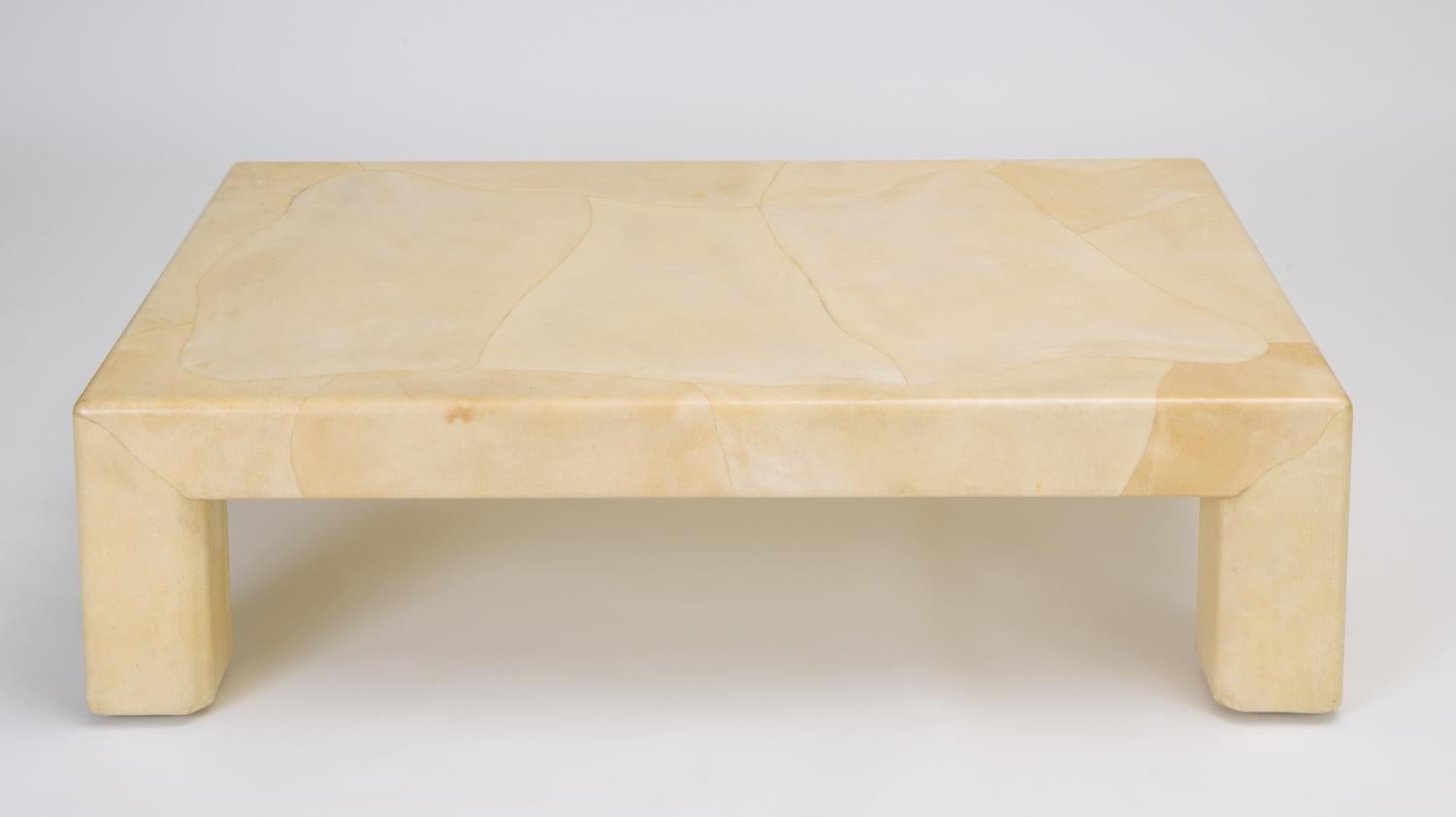 Chunky, oversize legs and shapely curves define this Karl Springer-Esque coffee table. Goatskin parchment is stretched over the wooden frame and finished with a high gloss lacquer. The edges of the legs and tabletop are softly rounded and small