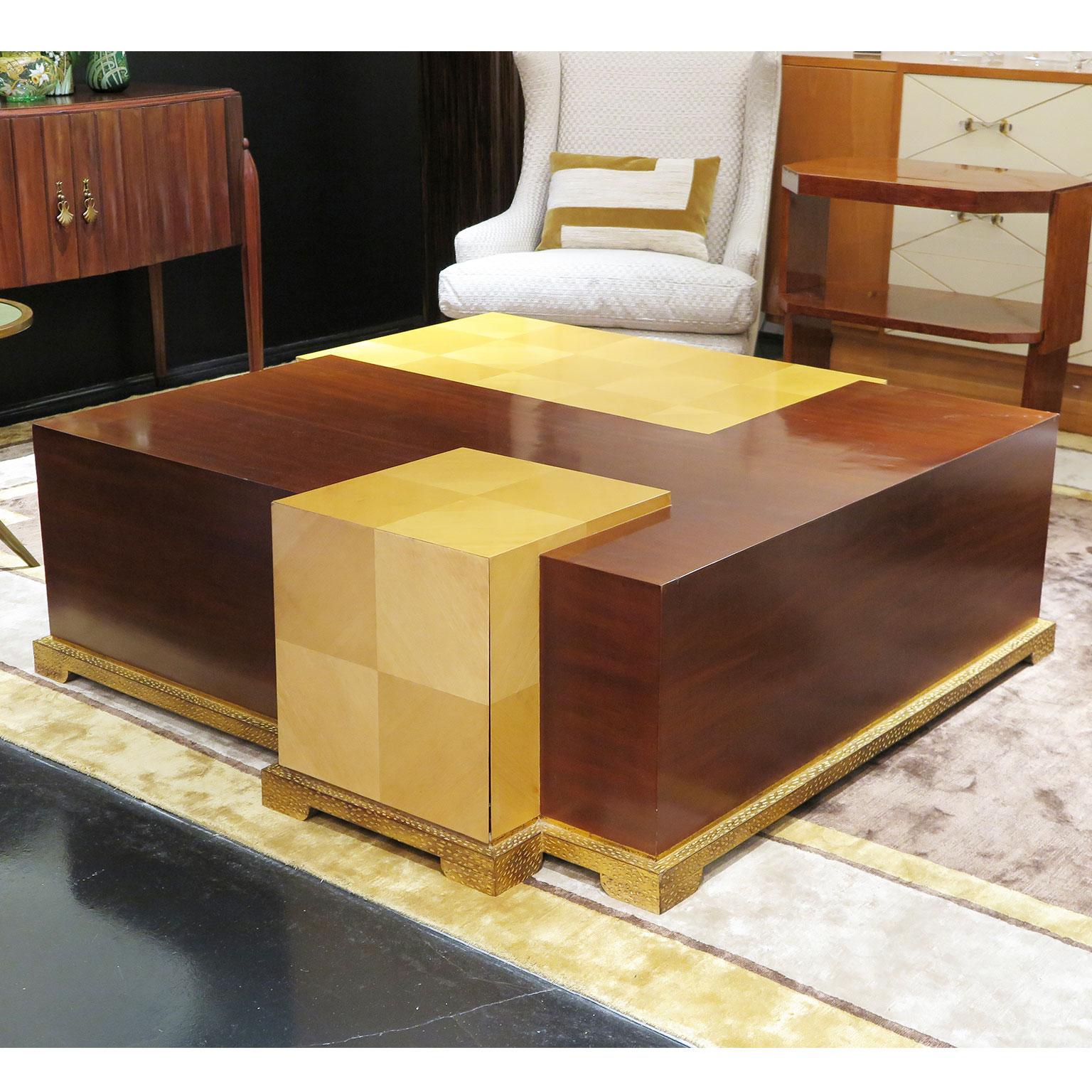 Large coffee table with overlapping squares and rectangles. Sycamore and mahogany levels with hammered wooden teardrop base in gold leaf. Hidden drawer in Sycamore cube.

Please note that this piece is in original condition.