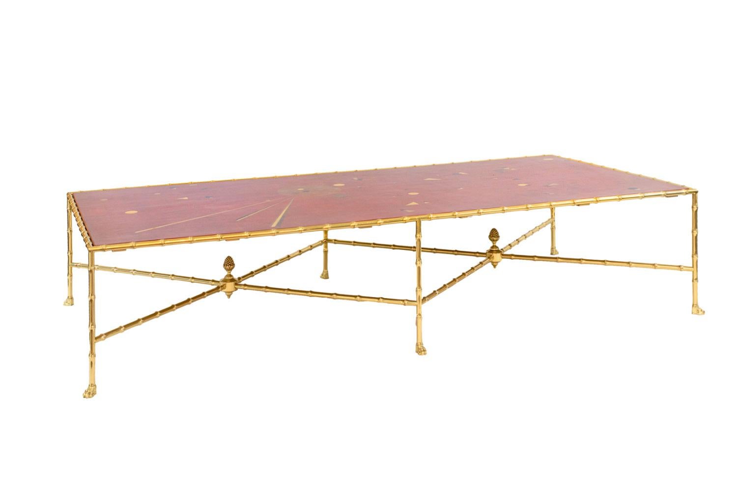 Large rectangular coffee table standing on six gilt brass bamboo shaped legs ending in lion paws and linked to each other by two X-bamboo stretchers centered of pine cones.
Red lacquer tray with geometrical motifs in black, white and gilt tones