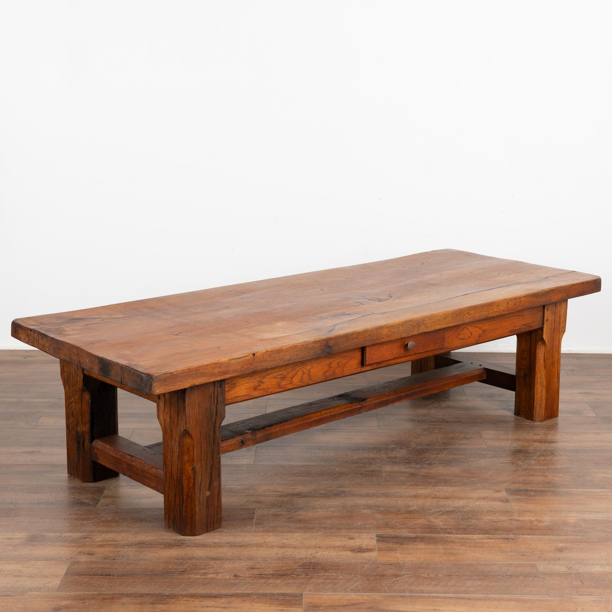The beauty of this French country coffee table with one drawer comes from the rich patina of the wood. Every crack, ding, old knot and stain all add to the depth and richness found in the thick top. Rests on heavy legs with a stretcher