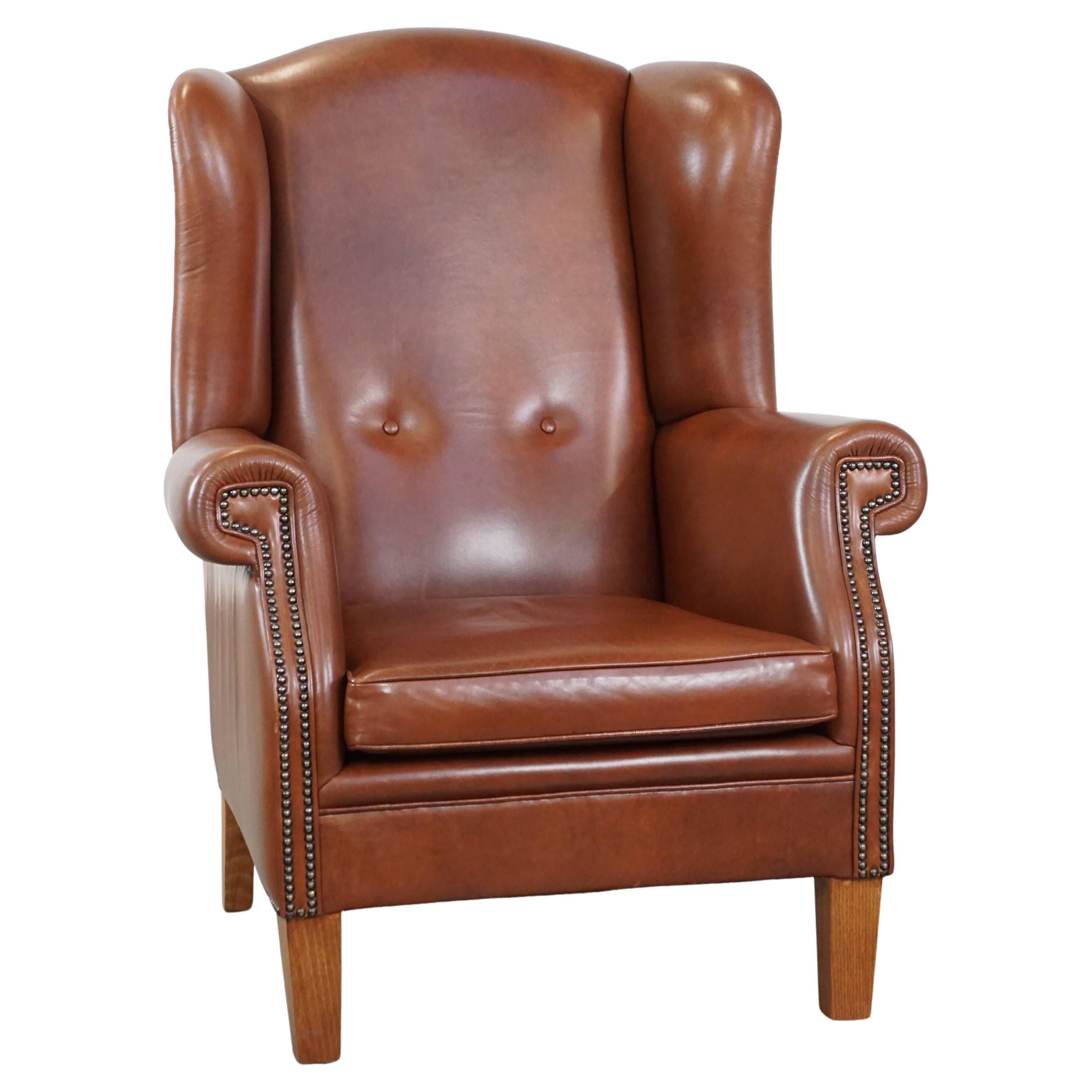 Large cognac-colored leather wingback chair in good condition in English style
