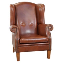 Large cognac-colored leather wingback chair in good condition in English style