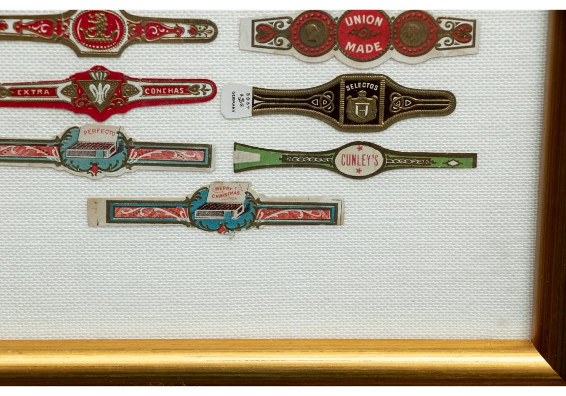Multicolored and gilt bands of different types. Including some Egyptian, Habana and Turkish (upper right ones with a steam ship and a river landscape). Mounted on white linen in a gilt frame.
H. 35