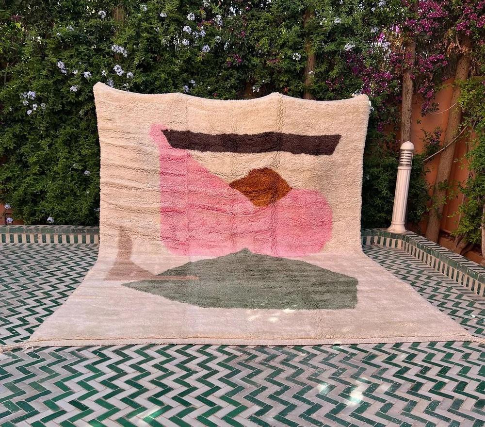 This large, modern handwoven Moroccan rug was made by hand by skilled artisans in the Atlas Mountains. It features a high quality, neutral cream wool base with a graphic, multi-colored abstract design unique to Moroccan style. Handmade on a loom