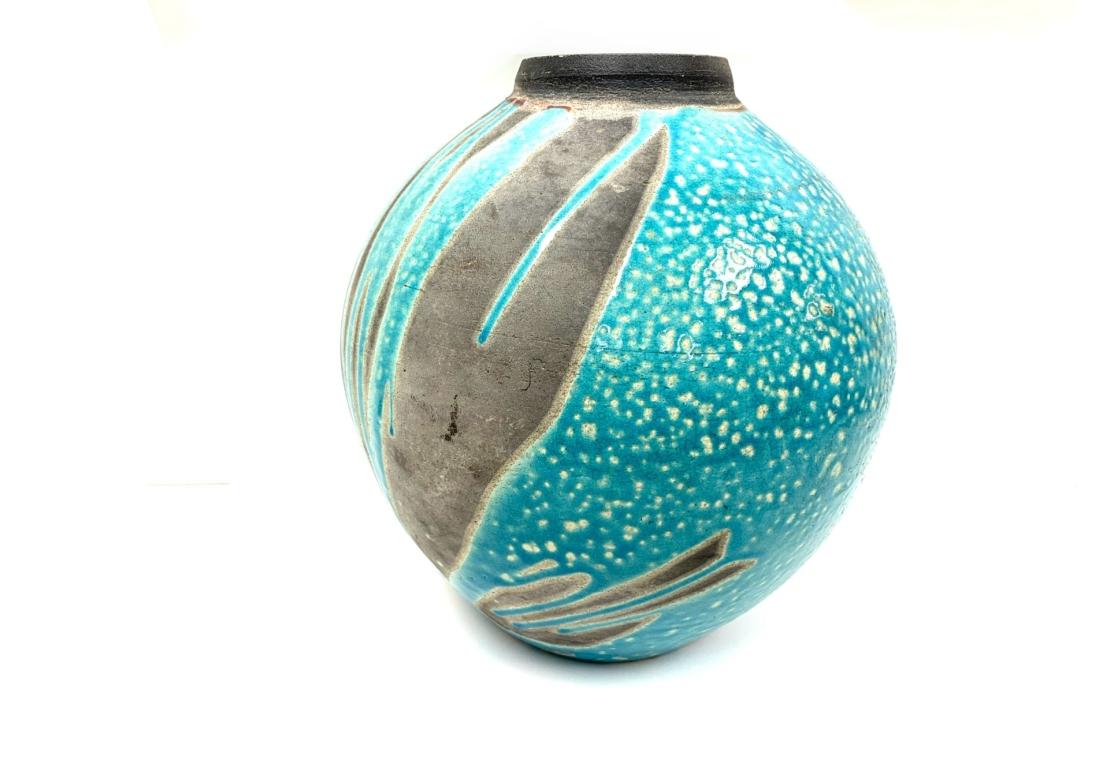 Ein großer Raku-Keramikkrug mit kräftiger türkisfarbener Emaille-Glasur, die eine kieselige Oberfläche hat und die grauen Biskuit-Töne akzentuiert.

Abmessungen: 11 1/2