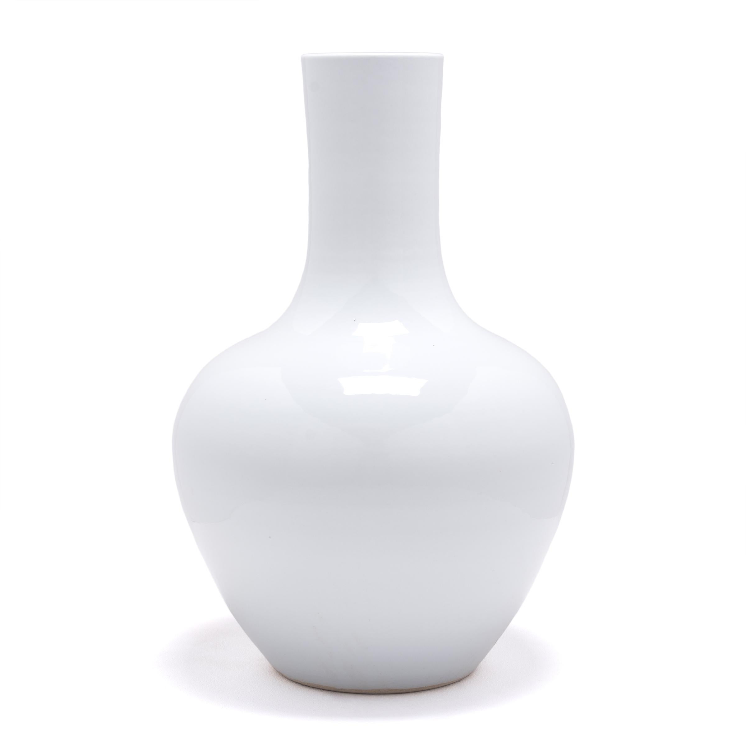 S'inspirant d'une longue tradition chinoise de céramiques monochromes, ce grand vase à col de cygne est recouvert d'une glaçure blanche froide. Le vase présente un corps arrondi avec des épaules hautes et un col cylindrique étroit, une forme