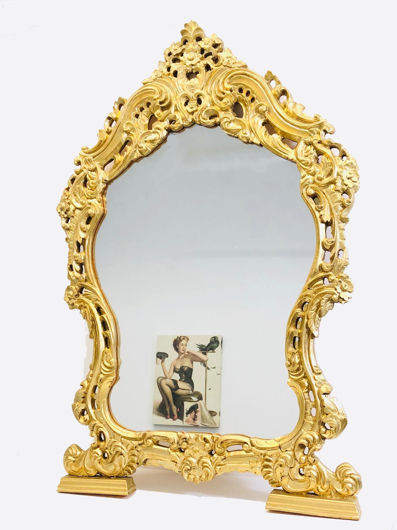 Stunning large Hollywood Regency style carved mirror. The giltwood frame surrounds a glass mirror. Made in Italy.