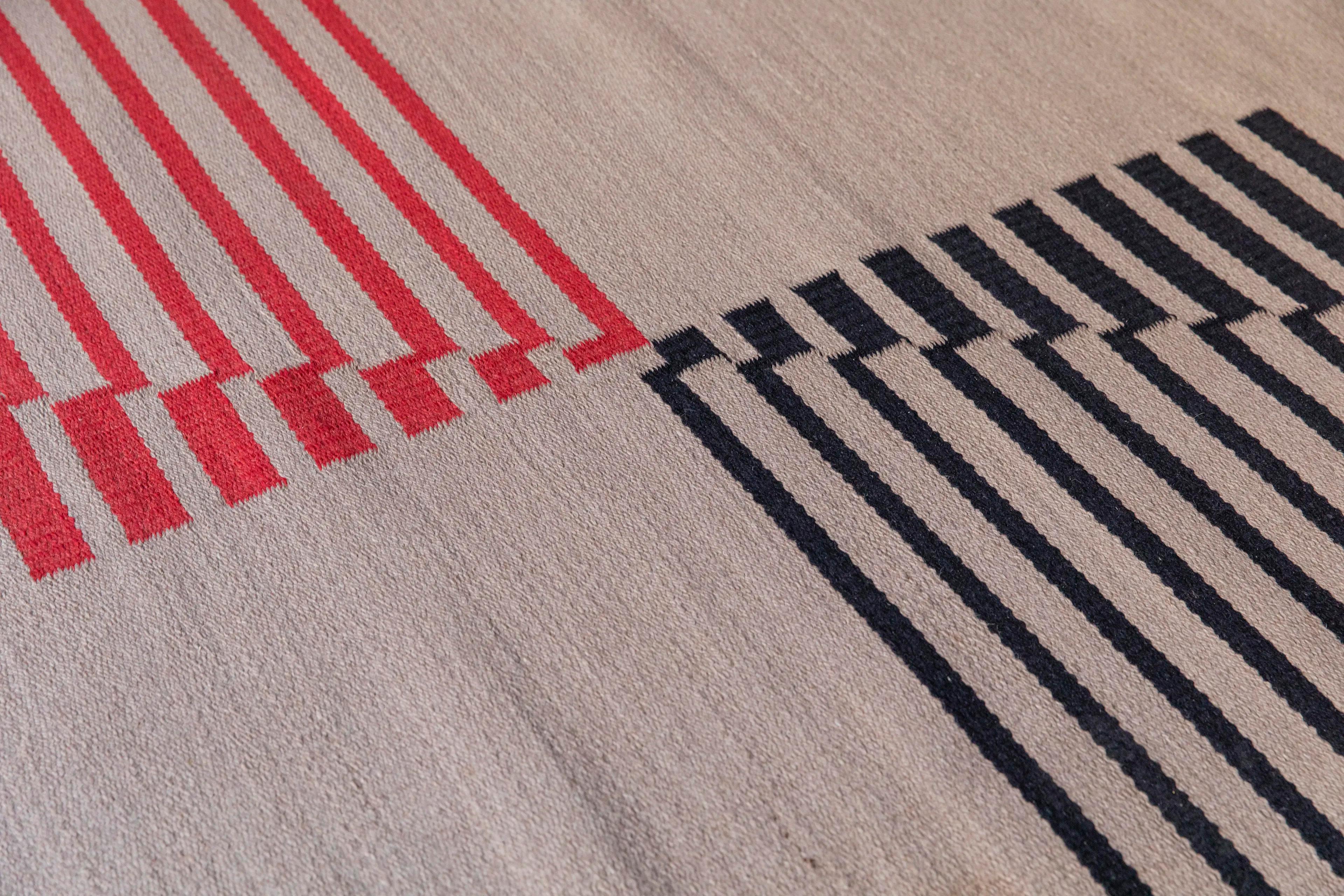 Esta alfombra a gran escala de Antonín Kybal es un ejemplo representativo del diseño textil constructivista de la Checoslovaquia de entreguerras, creada hacia 1935. La composición se define por una estricta disposición geométrica de campos lineales